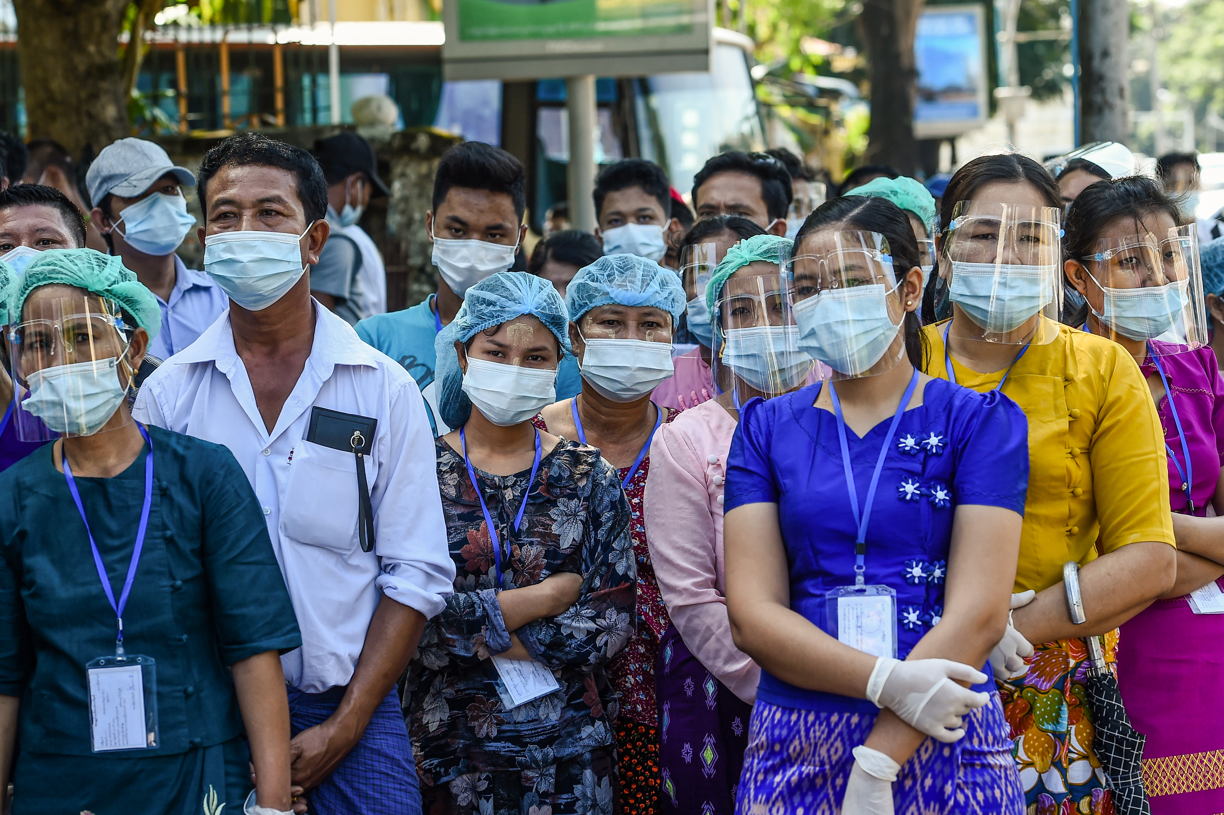 People wearing face shields, face masks and rubber gloves to prevent the spread of the COVID-19 wait to vote during the elections at a polling station in Yangon on November 8, 2020 [Ye Aung Thu/ AFP]