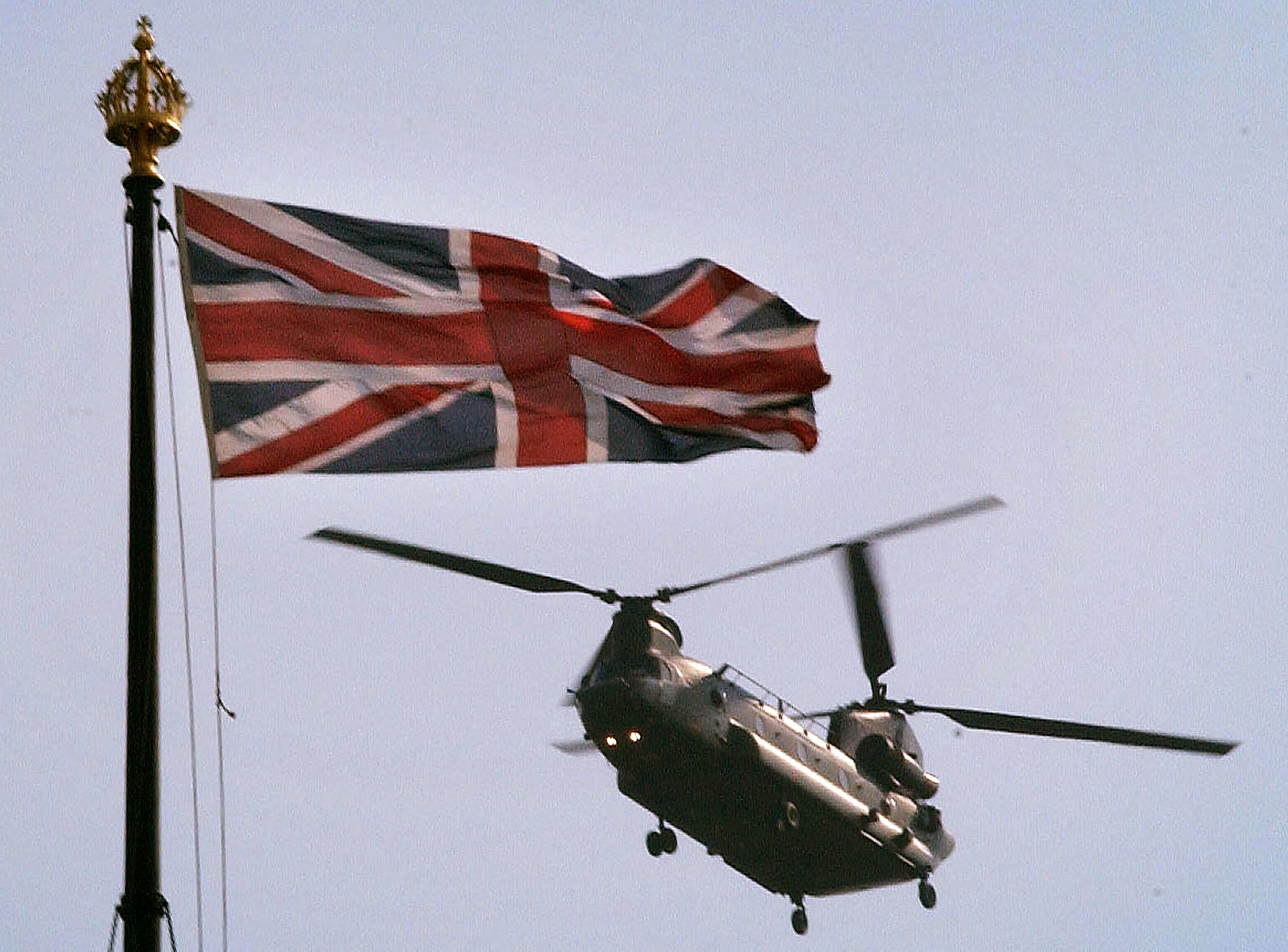 A British Army Chinook helicopter flies past the flag on top of the Houses of Parliament in central London April 10, 2002. British Prime Minister Tony Blair has pledged support for the U.S. in confronting Iraq over weapons of mass destruction but has stated to the Commons that the time was not yet right for military action. REUTERS/Stephen Hird SH/NMB