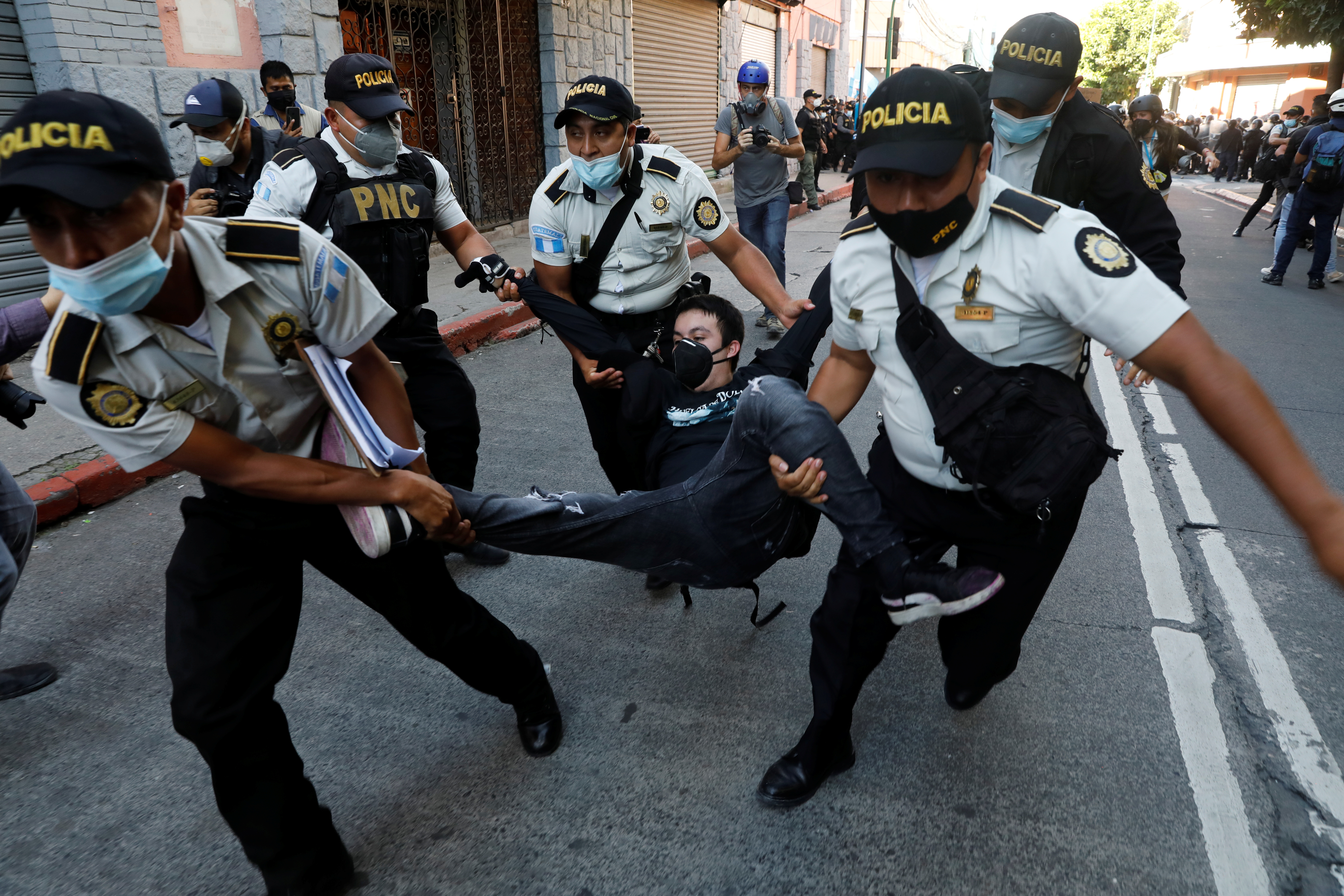 Police officers carry a demonstrator taking part in a protest demanding the resignation of Guatemalan President Alejandro Giammattei