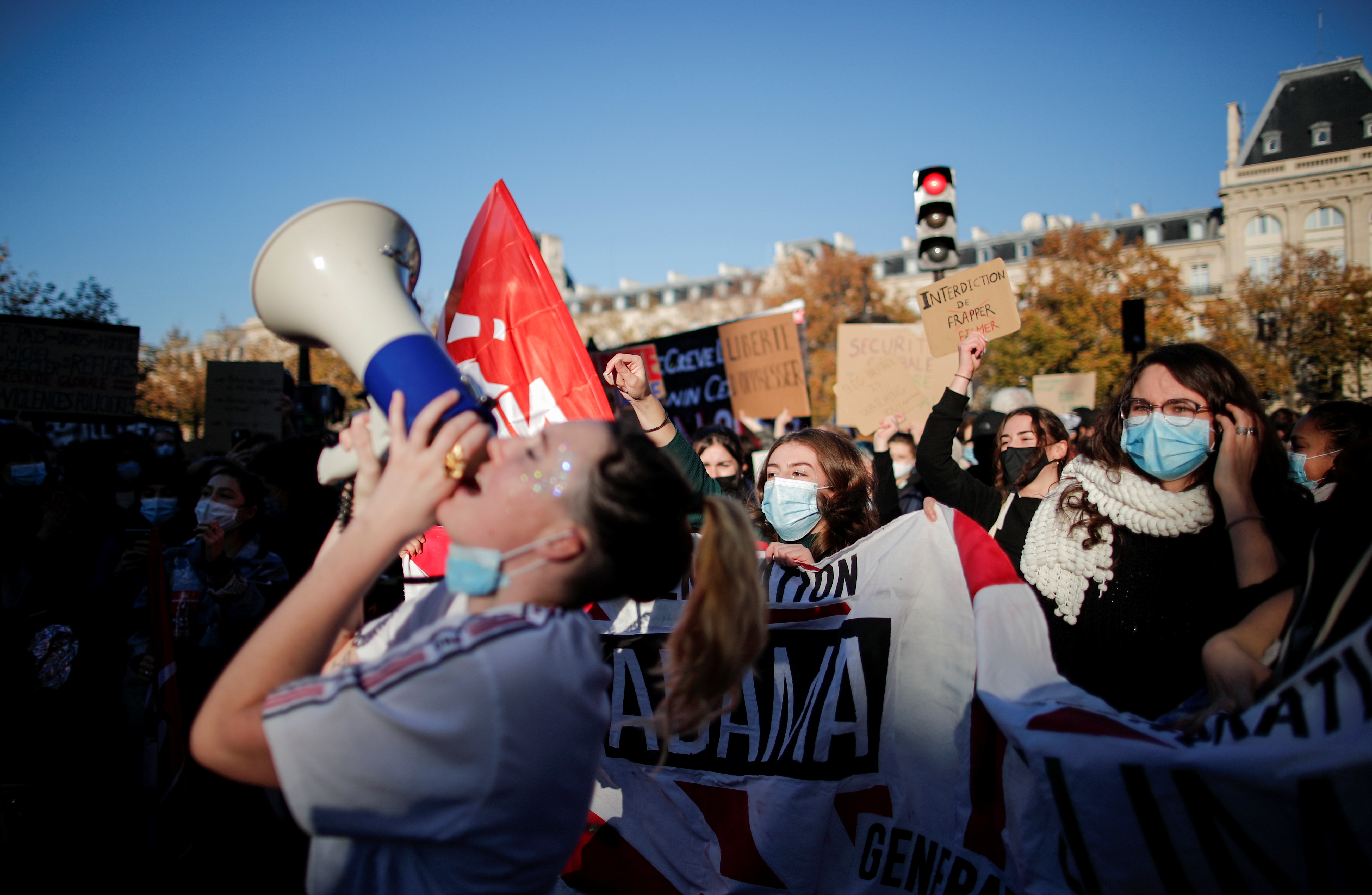 A protestor shouts slogans in a megaphone as people with banners and posters attend a demonstration against the "Global Security Bill' that rights groups say would make it a crime to circulate an image of a police officer's face and would infringe journalists' freedom in France, at the Place de la Republique in Paris, November 28, 2020. REUTERS/Benoit Tessier