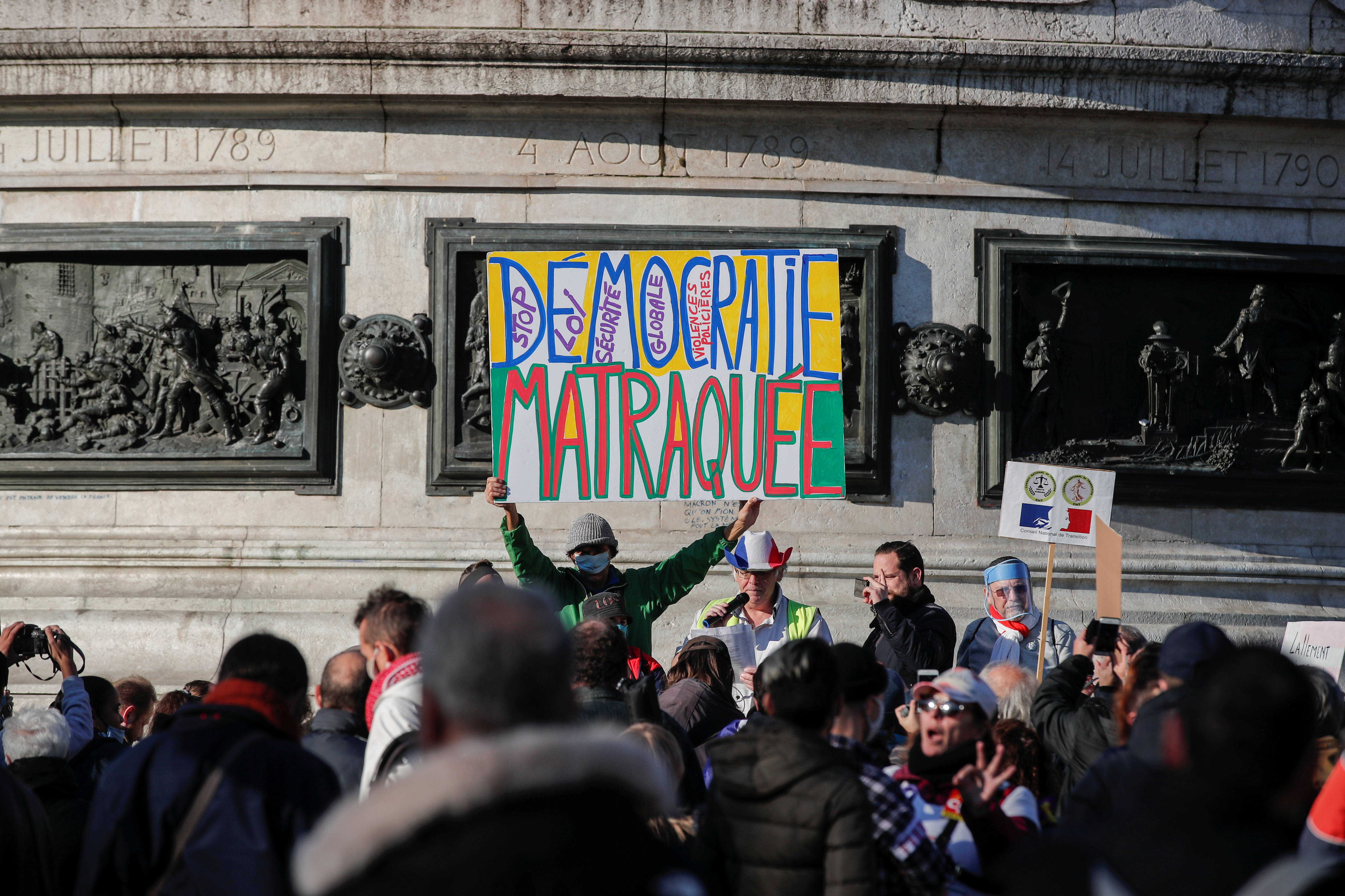People attend a demonstration against the "Global Security Bill' that rights groups say would make it a crime to circulate an image of a police officer's face and would infringe journalists' freedom in France, at the Place de la Republique in Paris, November 28, 2020. Banner reads: "Clubbed democracy". REUTERS/Benoit Tessier