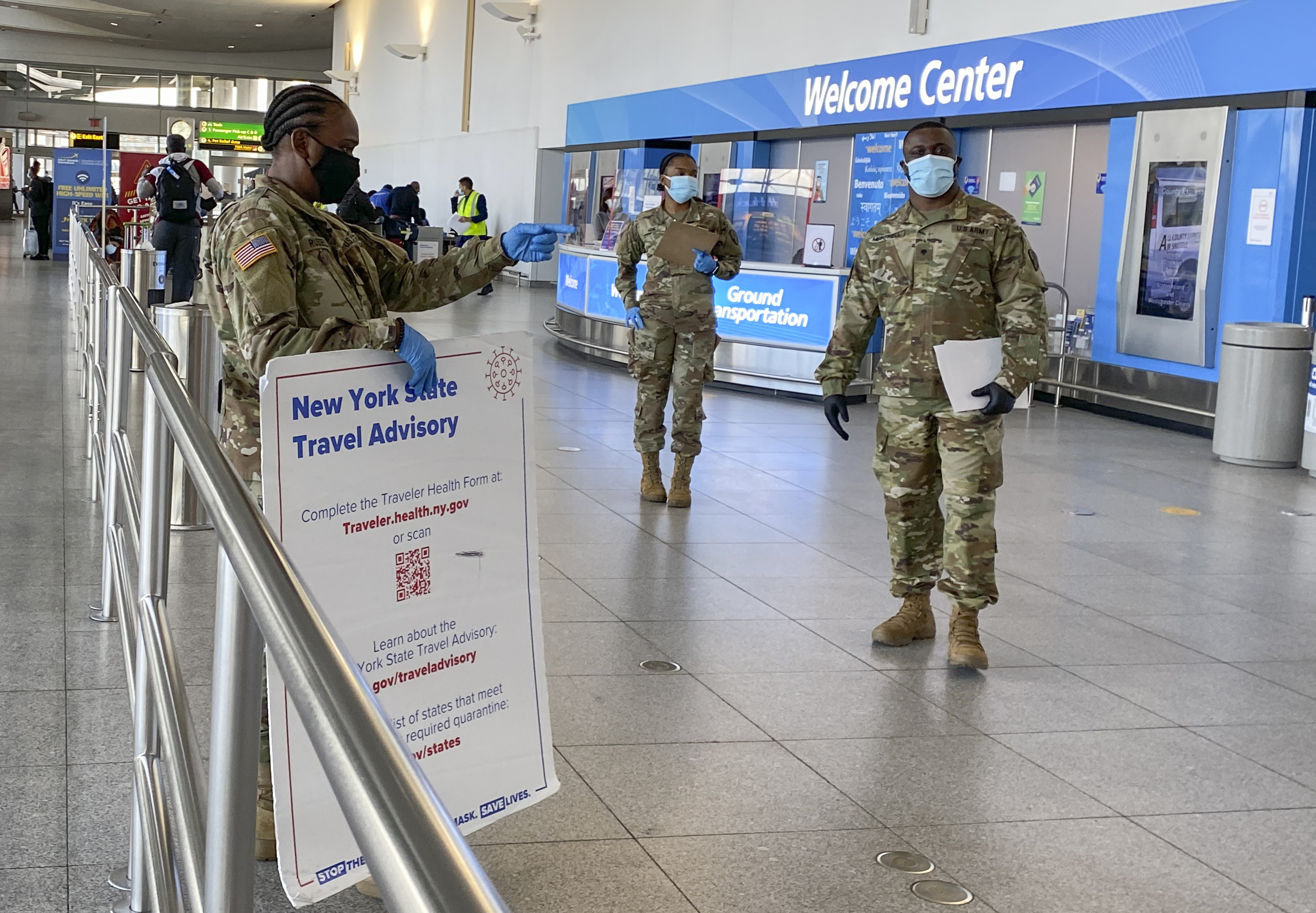 Military personnel hand out information to travellers arriving at JFK International airport in New York last week. The US is considering expanding a requirement for overseas passengers to have negative COVID-19 tests