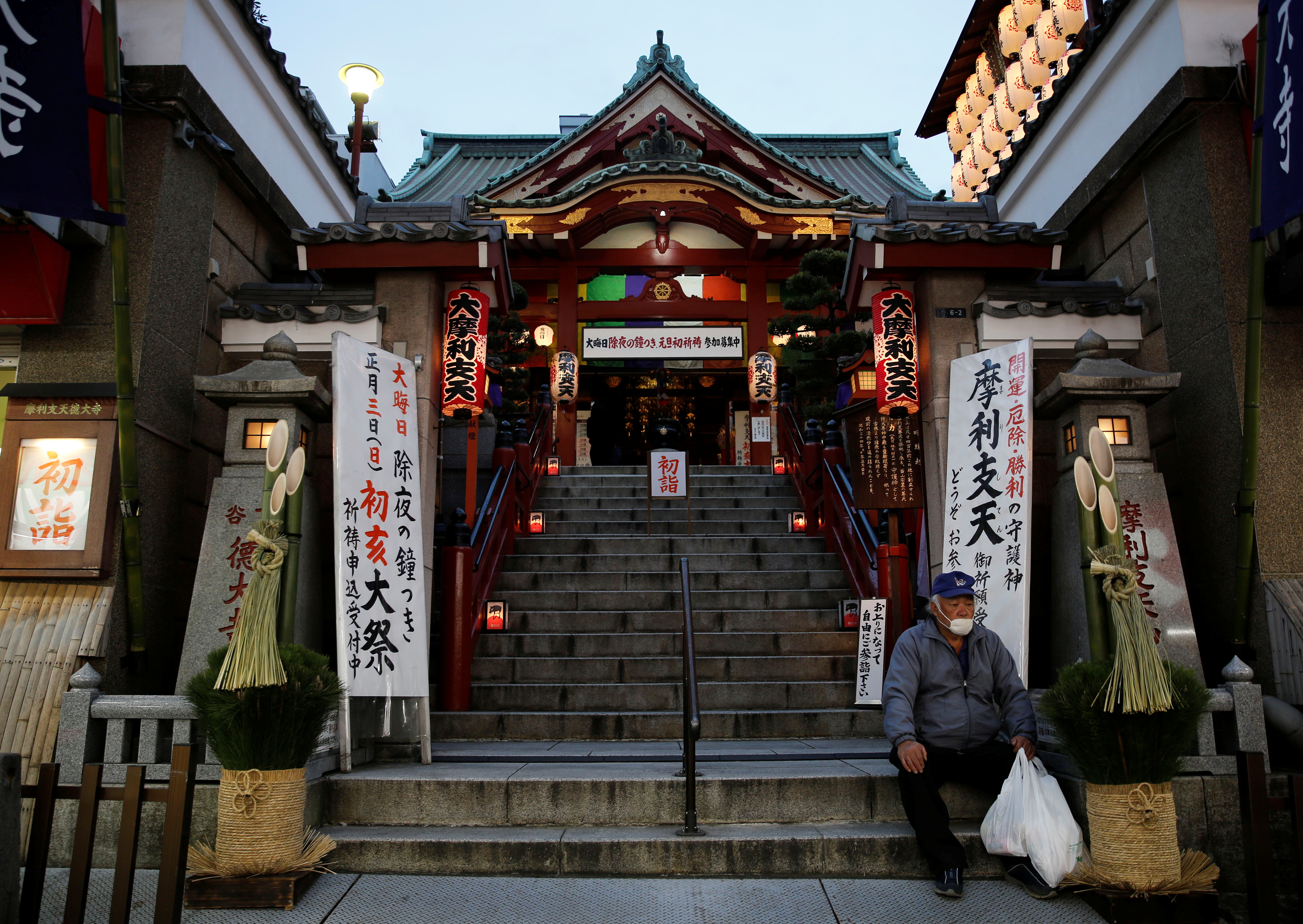 A man sits next to a new year’s decoration in front of a temple in Tokyo, Japan
