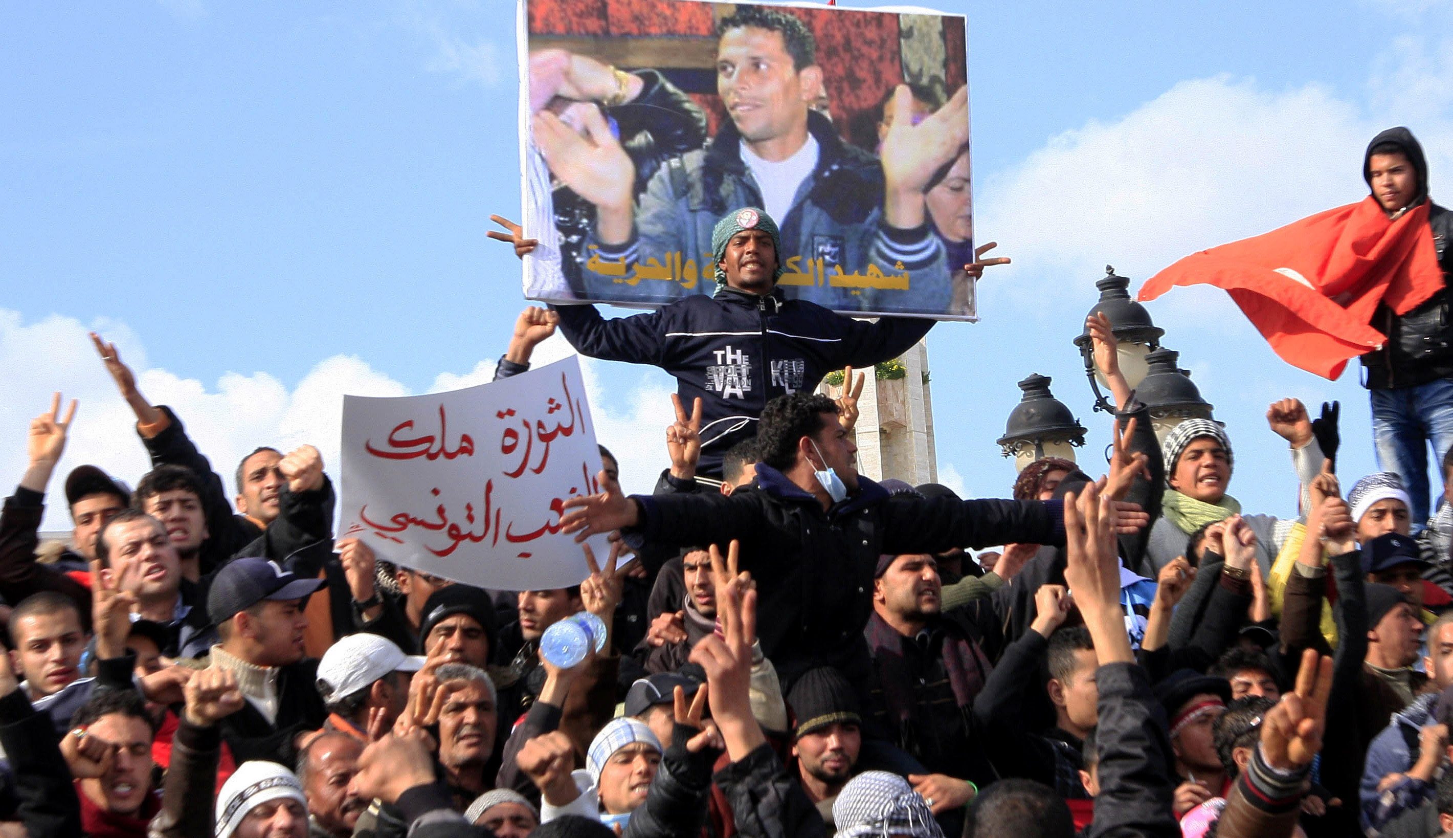In a photo from January 2011, Tunisian protesters demonstrate beneath a poster of Mohamed Bouazizi, near the prime minister's office in Tunis [File:Salah Habibi/AP Photo]