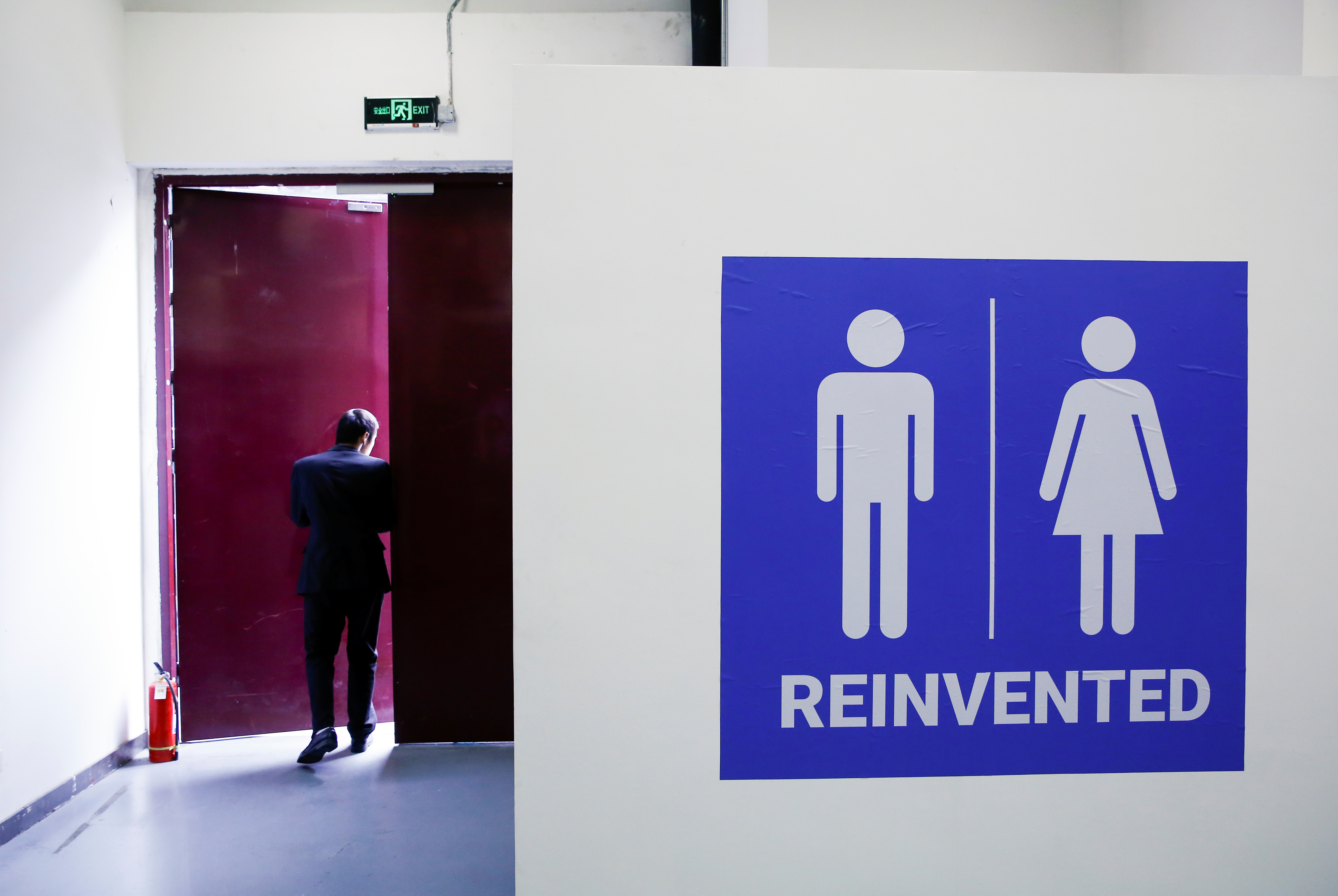 A man walks near a toilet sign at the Reinvented Toilet Expo showcasing sewerless sanitation technology in Beijing, China November 6, 2018. [Thomas Peter/Reuters]