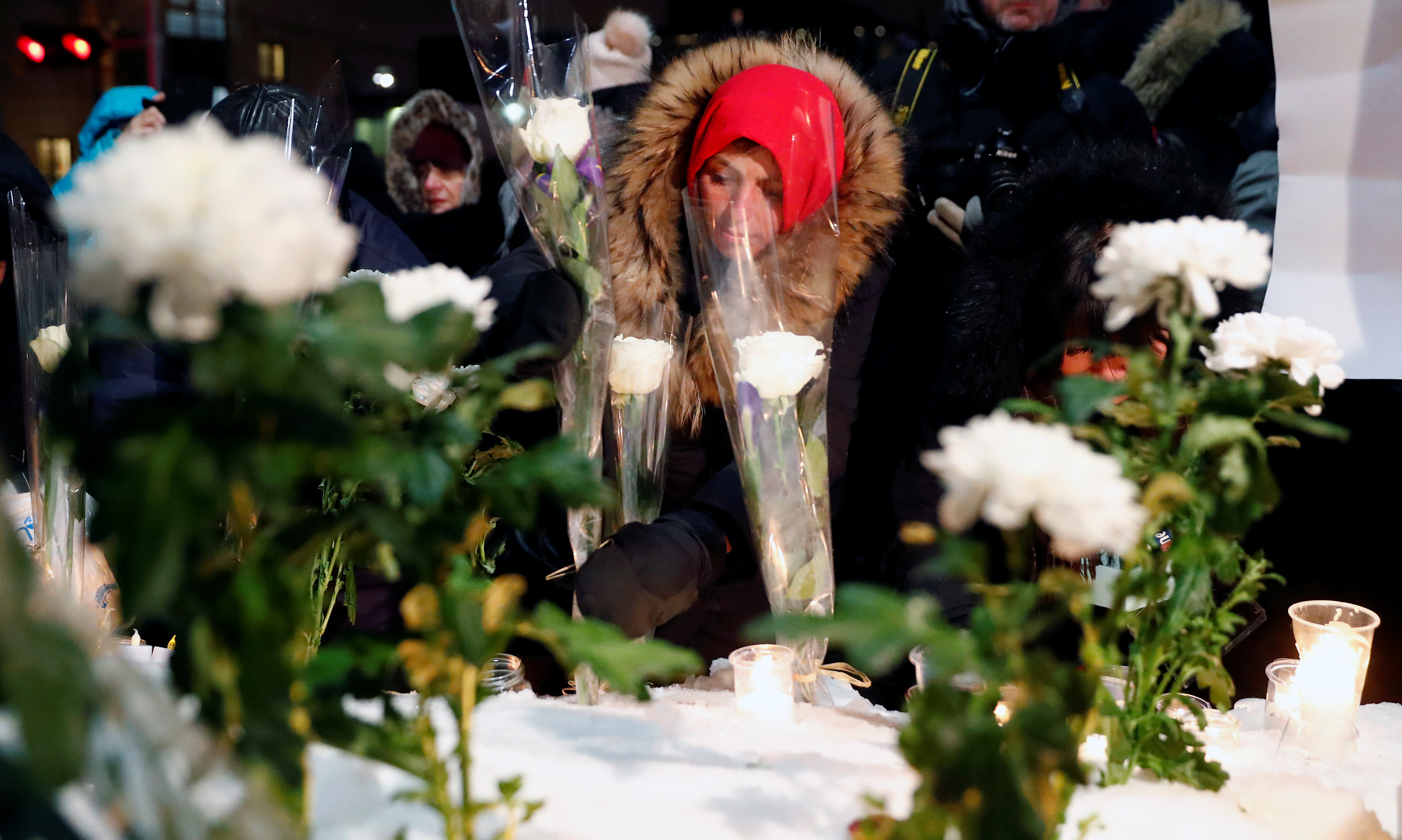 A woman leaves a flower during the one-year anniversary vigil for the Quebec City mosque victims