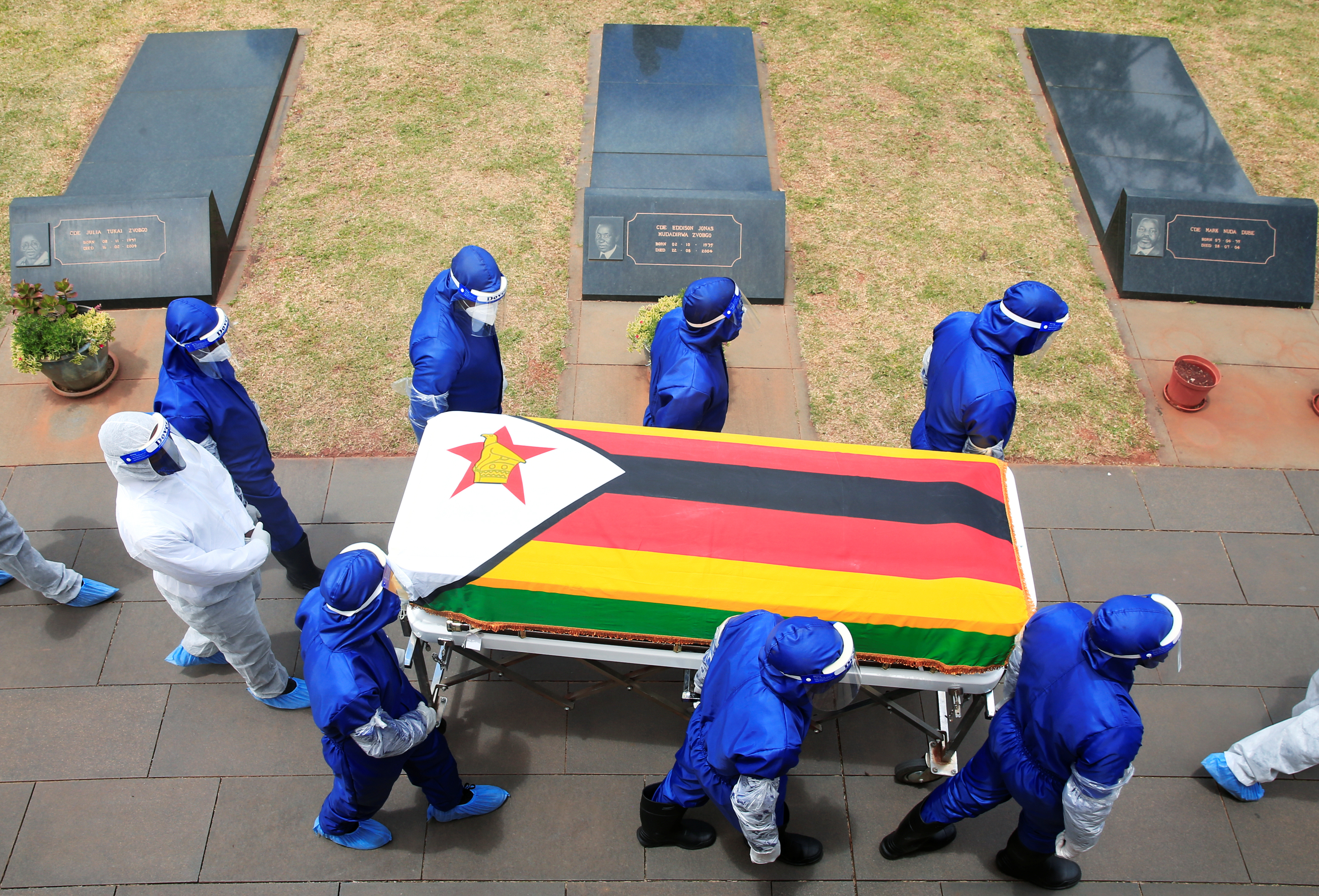 Pallbearers in Harare carry a coffin at the burial of two cabinet ministers and a retired general who died after contracting COVID-19 [Philimon Bulawayo/Reuters]