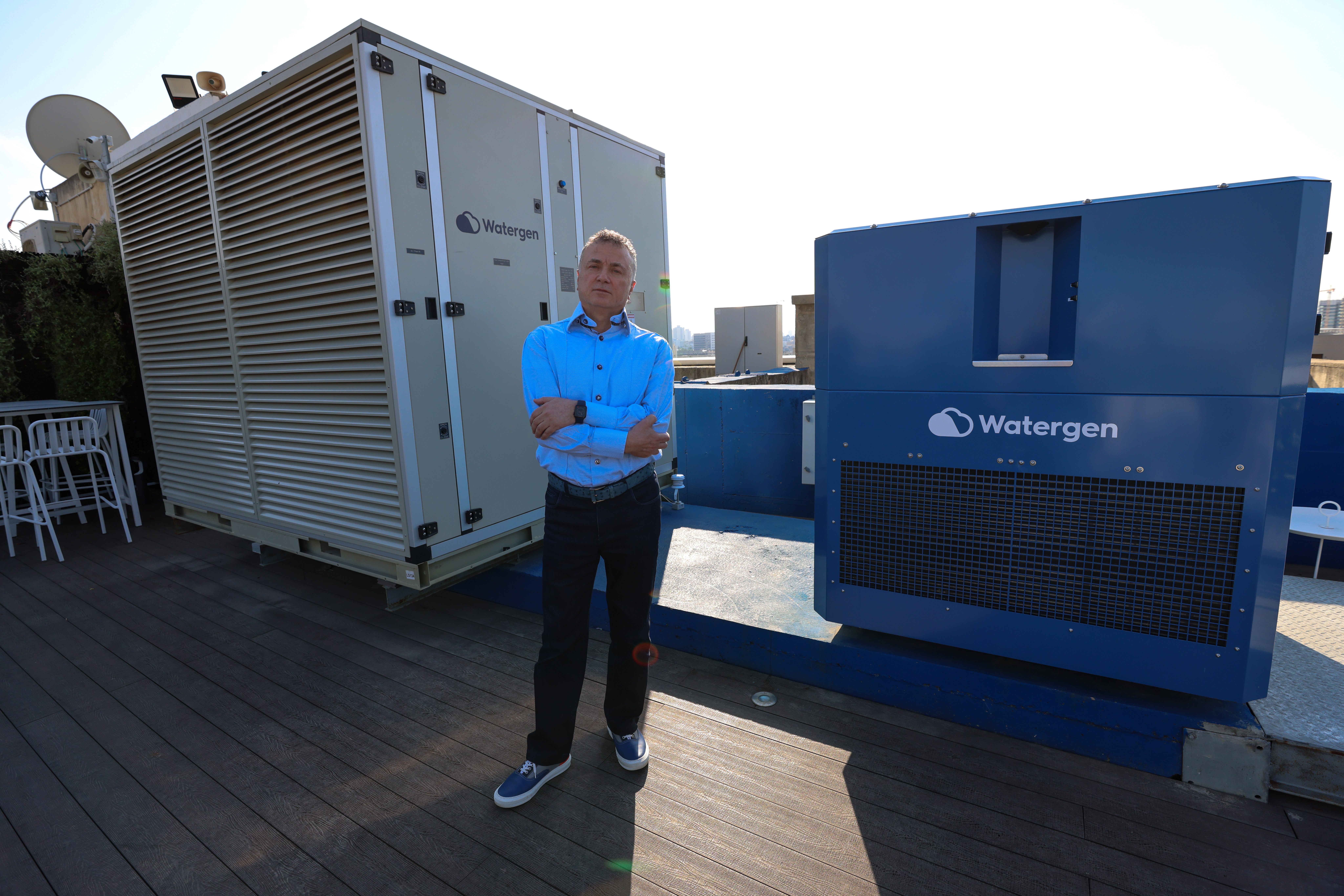 Watergen CEO Michael Mirilashvili stands by one of his company's machines that transform air humidity into drinkable water [Emmanuel Dunand/AFP]