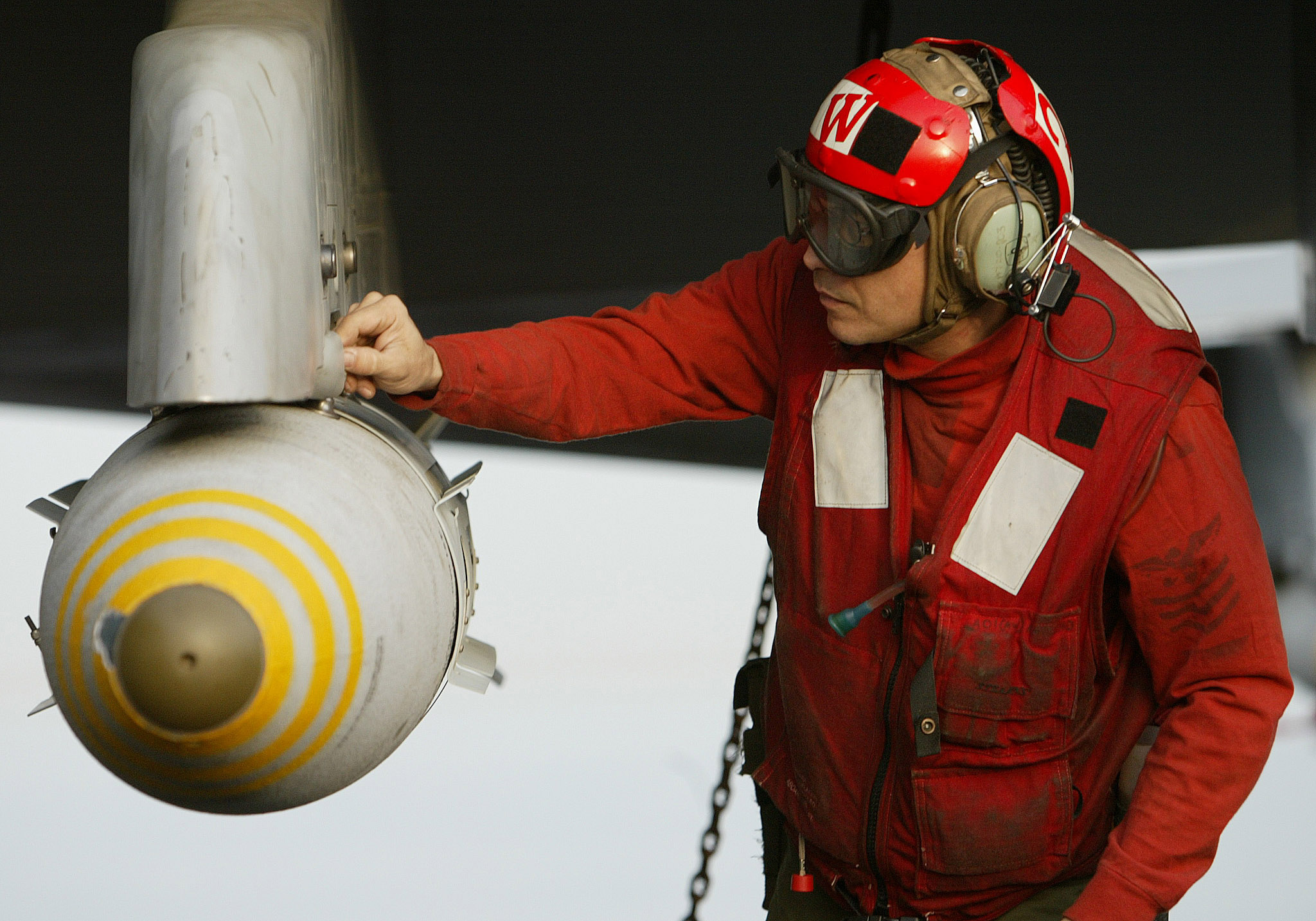 A US aviation ordnanceman makes a final check on a 500-pound JDAM satellite guided bomb on the wing of an F/A-18 Hornet fighter jet