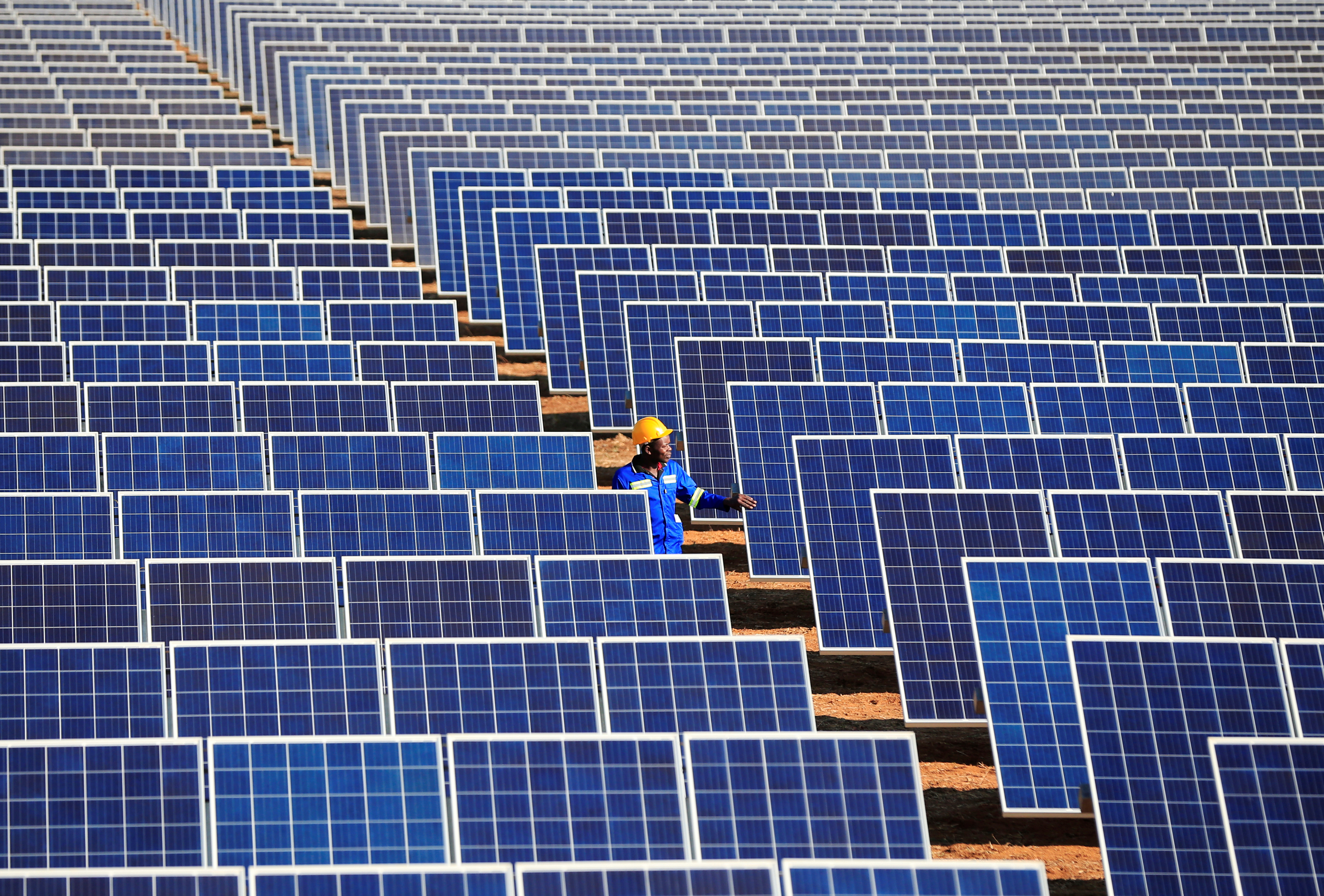 A worker walks between solar panels at Centragrid power plant in Nyabira, Zimbabwe, June 23, 2020. REUTERS/Philimon Bulawayo