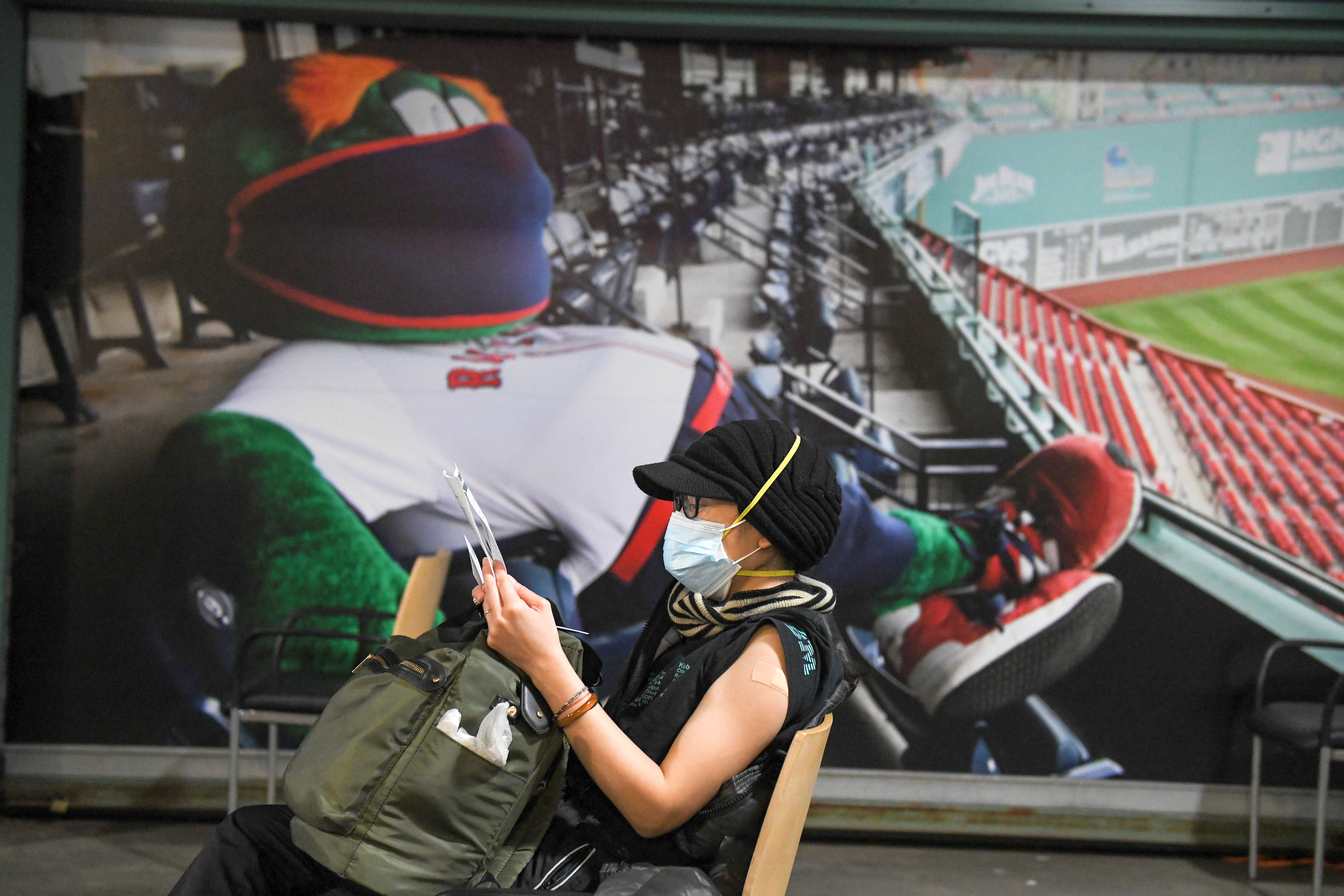 A woman waits in the observation area after receiving a Pfizer-BioNTech COVID-19 vaccine at a mass COVID-19 vaccination site being set up at Fenway Park in Boston [Faith Ninivaggi/Reuters]