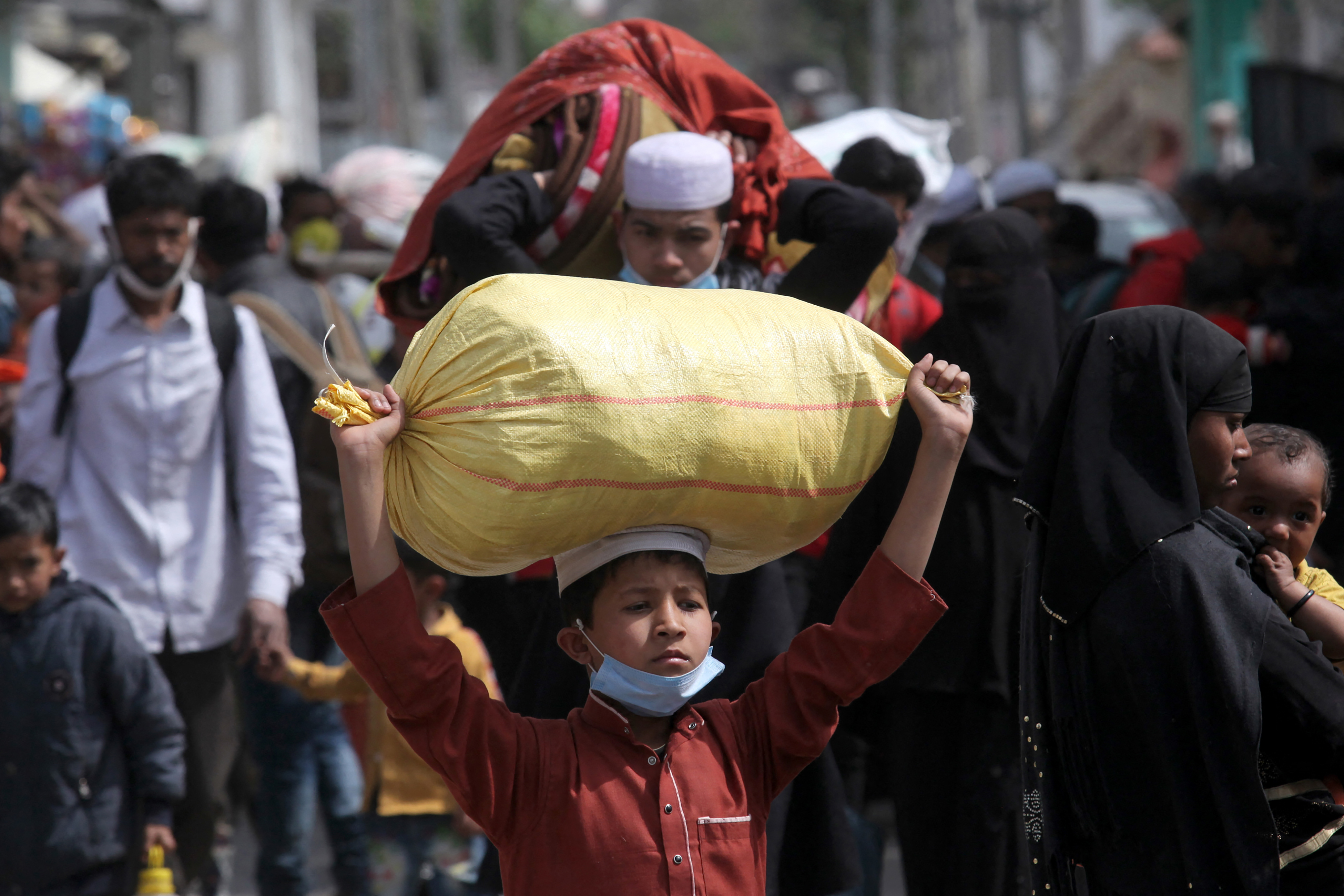 Rohingya carry their belongings as they leave a refugee camp in Jammu [Rakesh Bakshi/AFP]