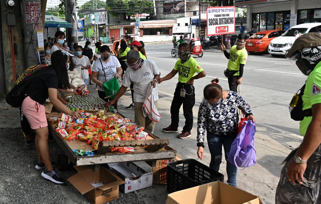 Residents collect free food packets from a food bank run by volunteers called a 'community pantry' along a road in suburban Manila [Ted Aljibe/AFP]
