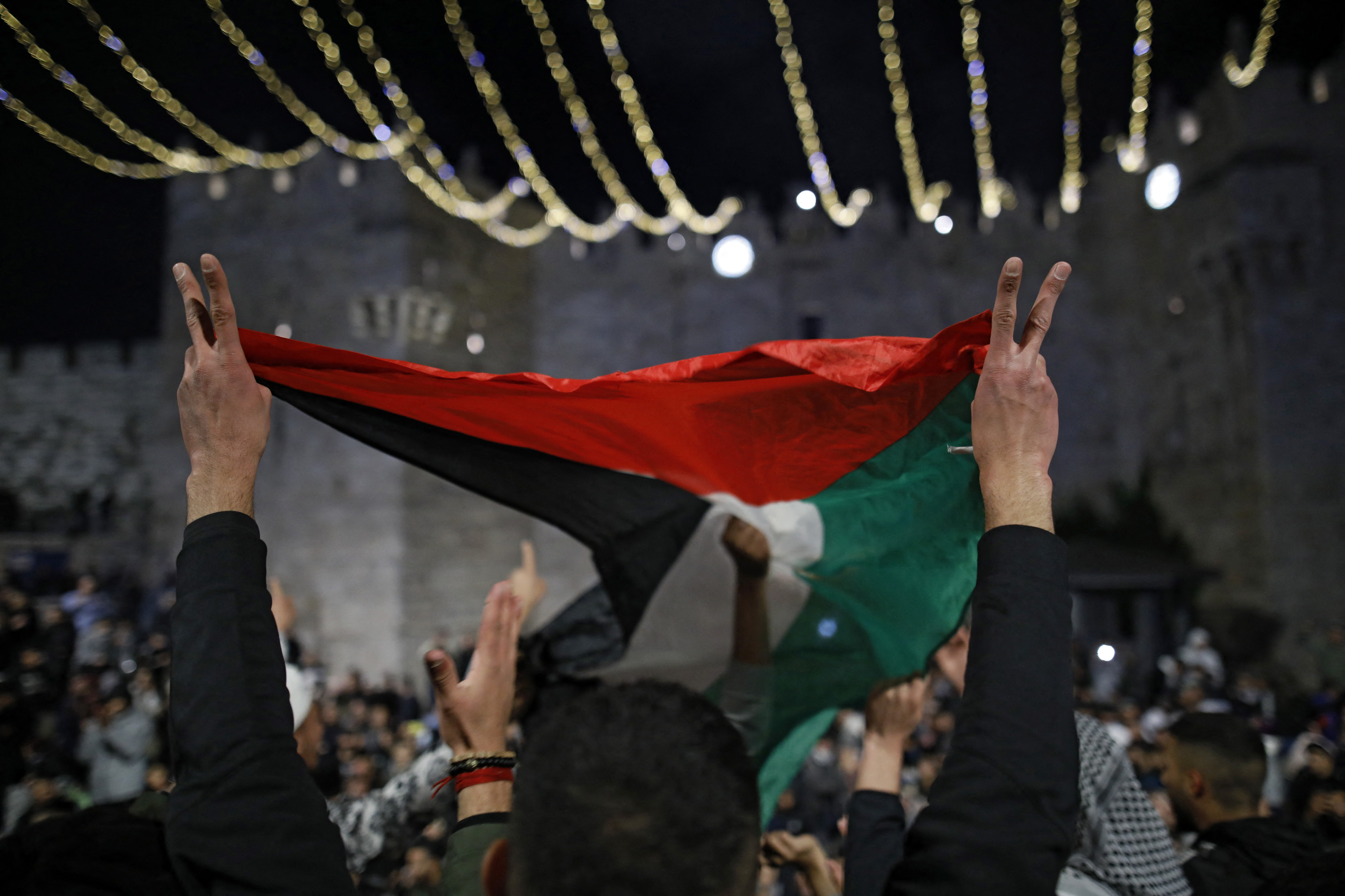 Palestinian protesters wave the national flag outside the Damascus Gate in Jerusalem's Old City on April 26, 2021 [AFP/Ahmad Gharabli]
