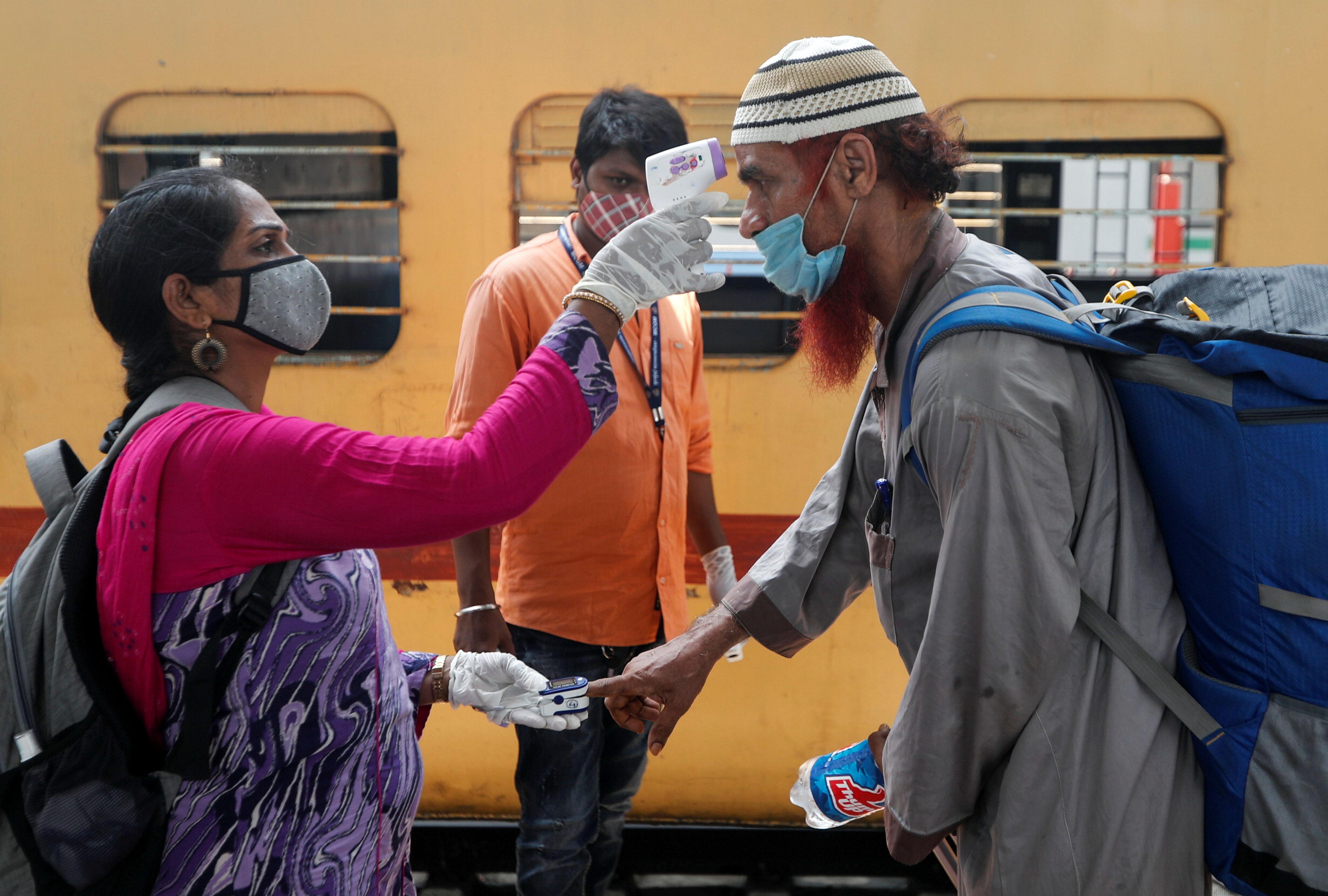 A health worker checks a passenger's temperature and pulse at a railway station platform in Mumbai, India [Francis Mascarenhas/Reuters]