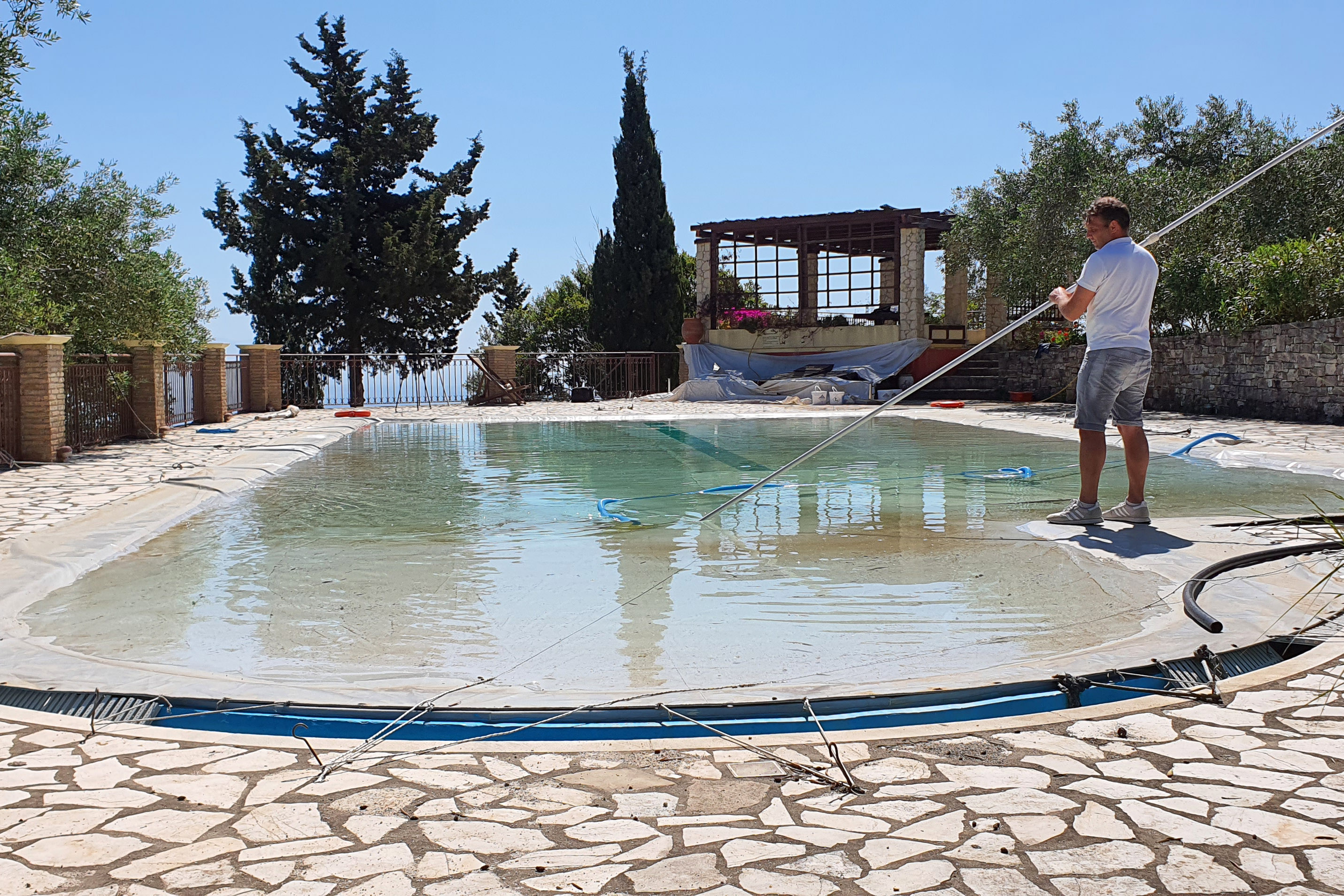 On Paxoi island, which is south of Corfu, Srtefanos Fougaros cleans his pool as he prepares to rent out his villas