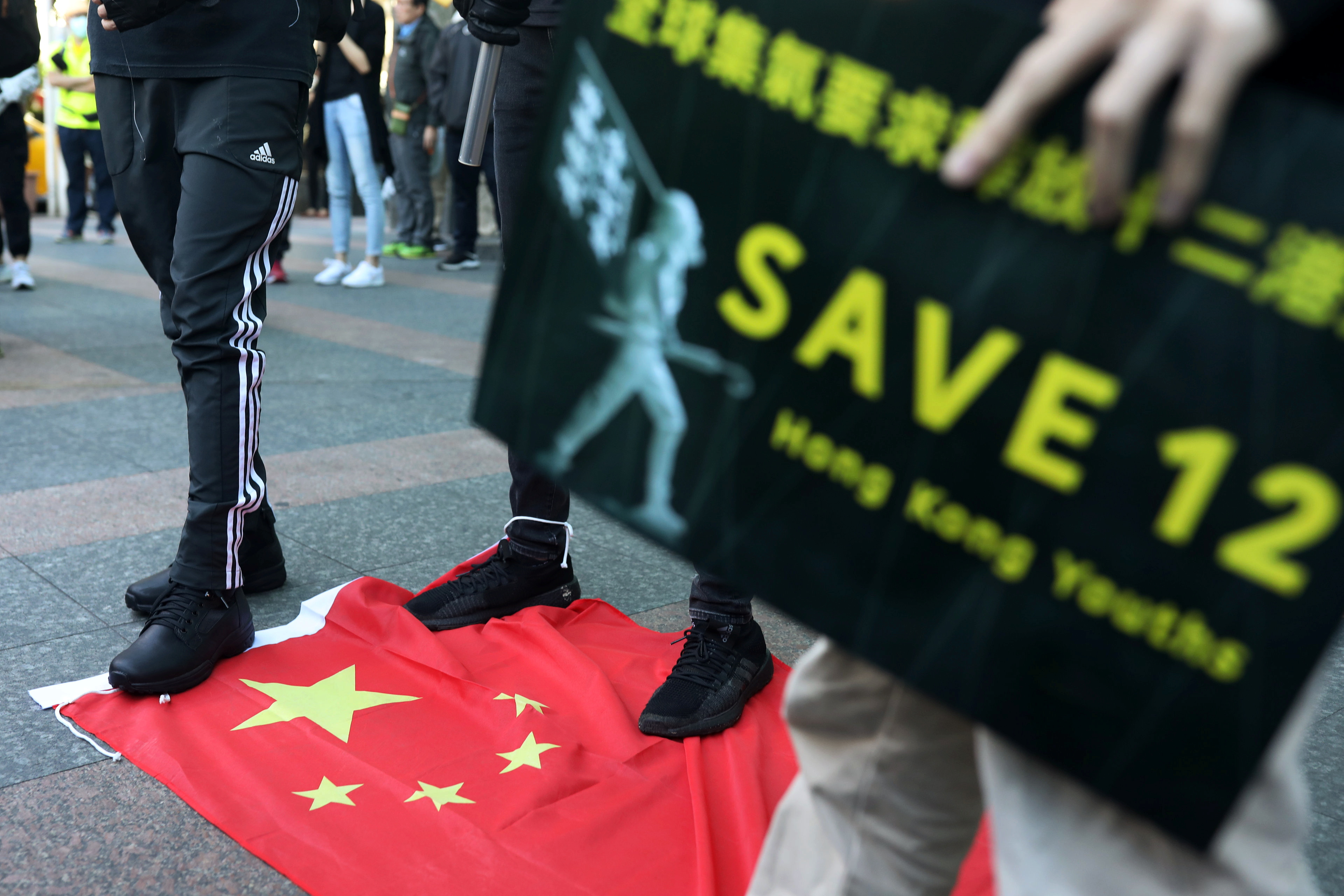 Protesters stand on a Chinese flag during a rally in Taipei calling on China to release 12 Hong Kongers arrested at sea by mainland authorities