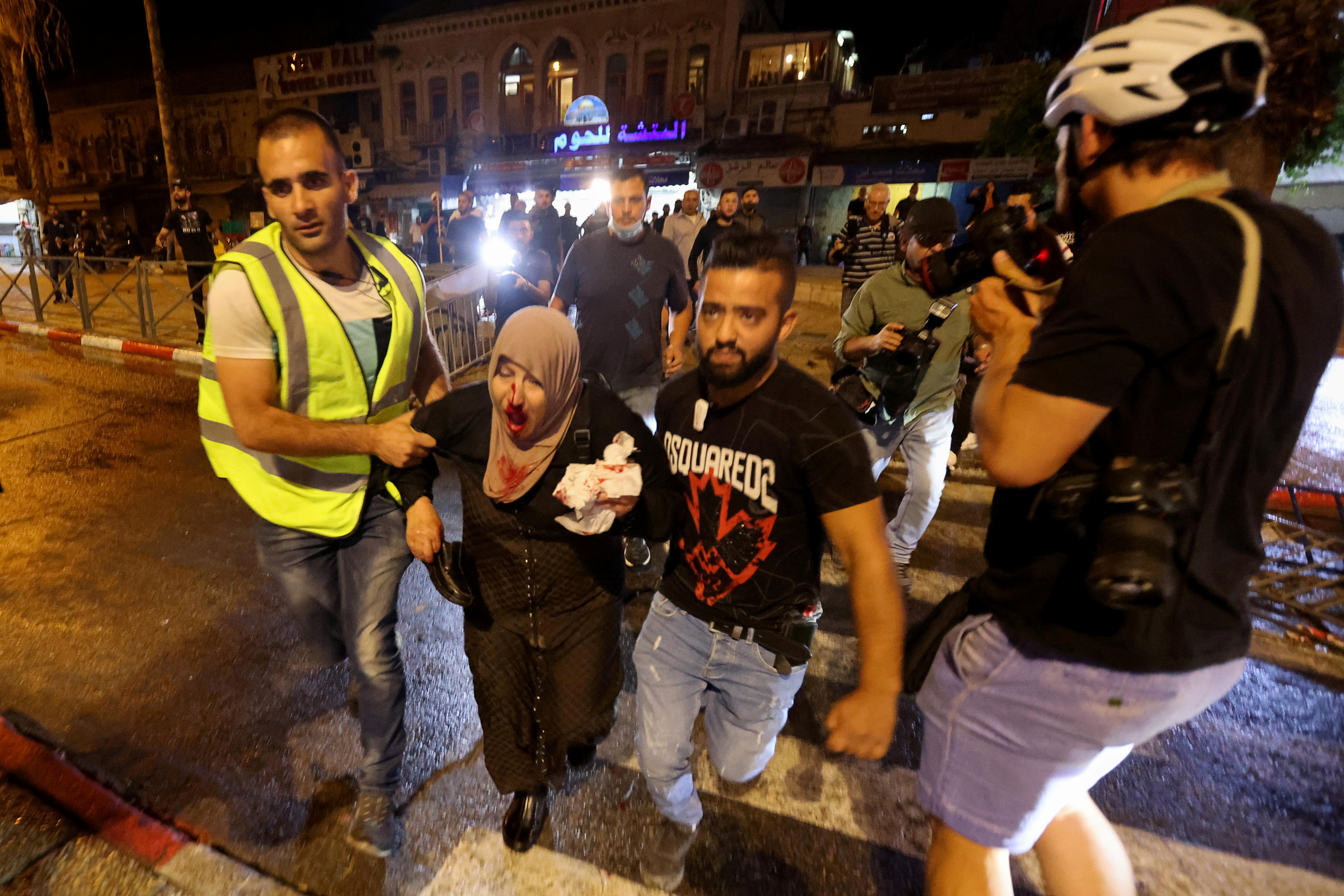 An injured Palestinian woman is evacuated during clashes with Israeli police near Damascus Gate on Laylat al-Qadr during the holy month of Ramadan, in Jerusalem's Old City on May 8, 2021 [Reuters/Ronen Zvulun]