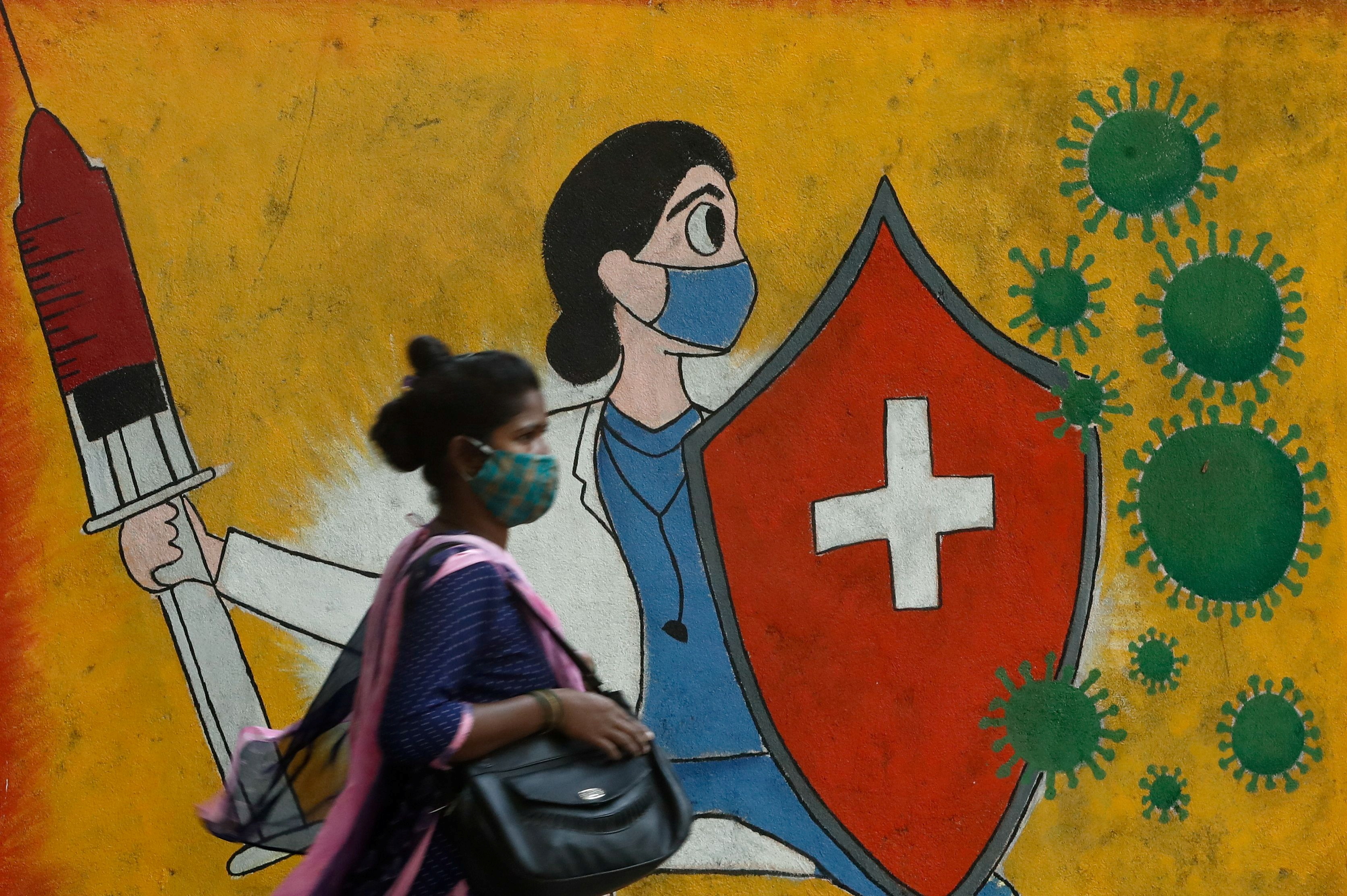A woman walks past a graffito on a street amid the spread of the coronavirus disease in Mumbai [Francis Mascarenhas/Reuters]