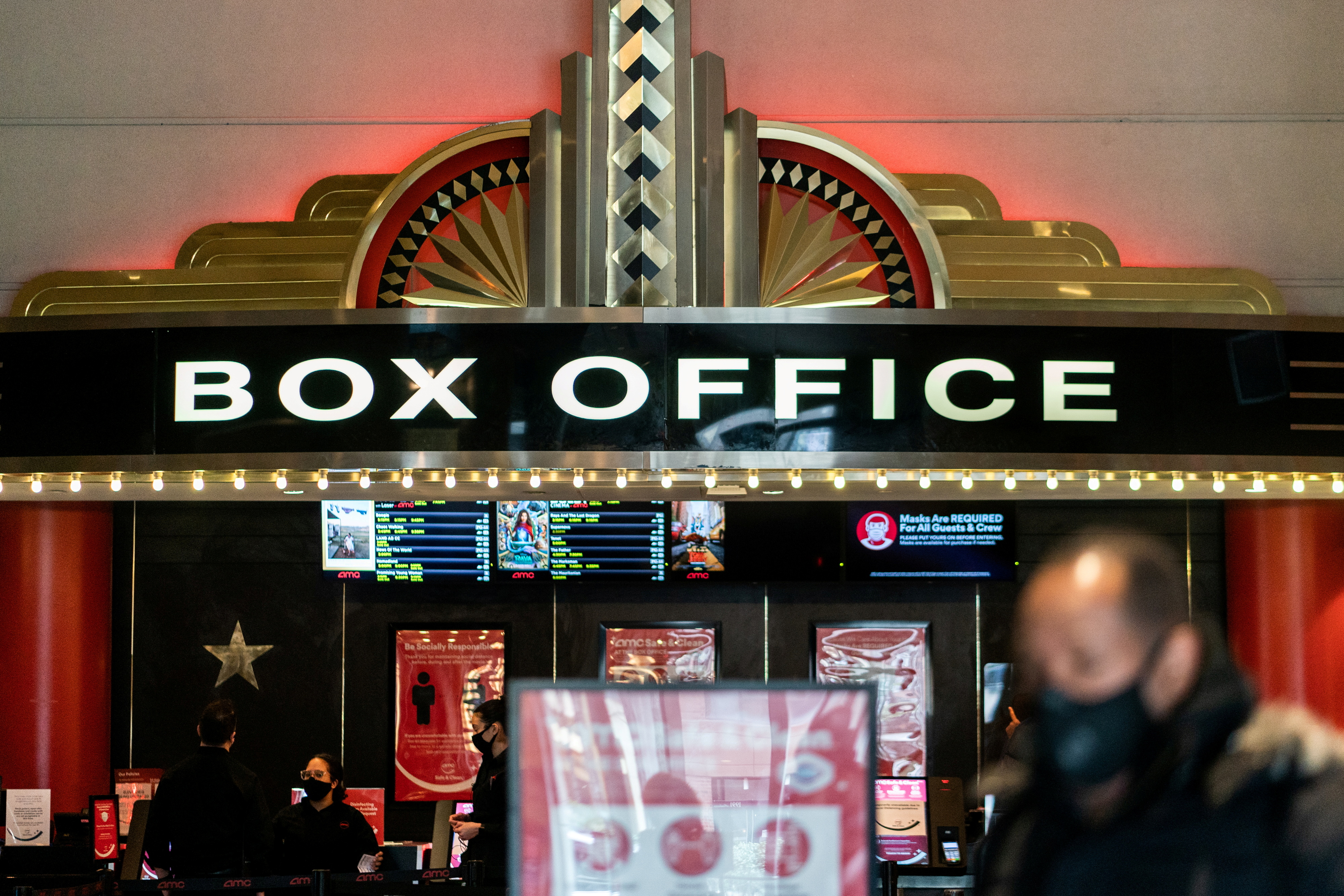 A guest purchases a ticket in front of a box office at AMC movie theatre in Lincoln Square, amid the coronavirus disease (COVID-19) pandemic, in the Manhattan borough of New York City, New York, US, March 6, 2021 [File: Jeenah Moon/Reuters]