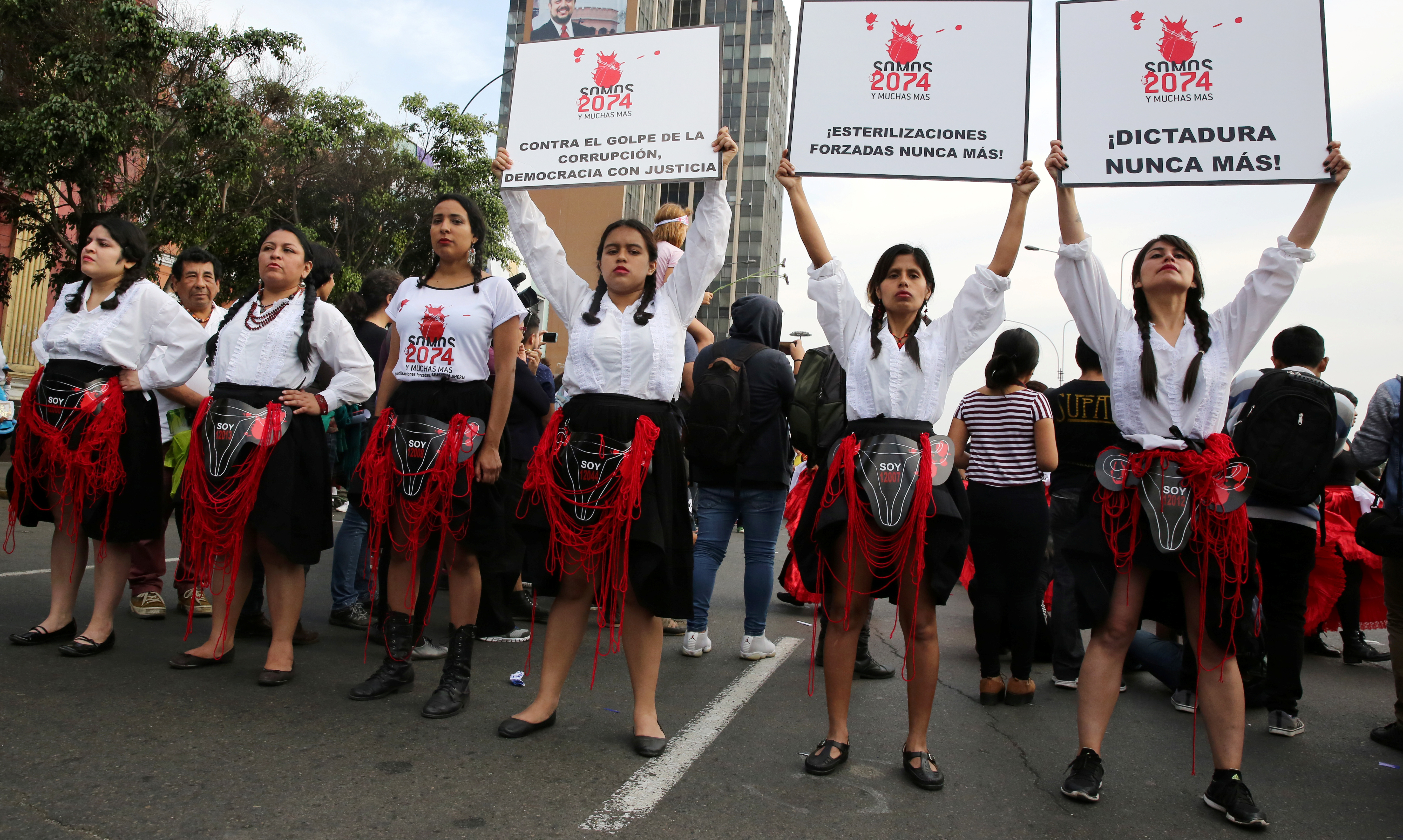 Women hold signs reading 'We are 2,074 and more, forced sterilisations never again' during a protest against violence against women in Lima, Peru, in 2017 [File: Mariana Bazo/Reuters]
