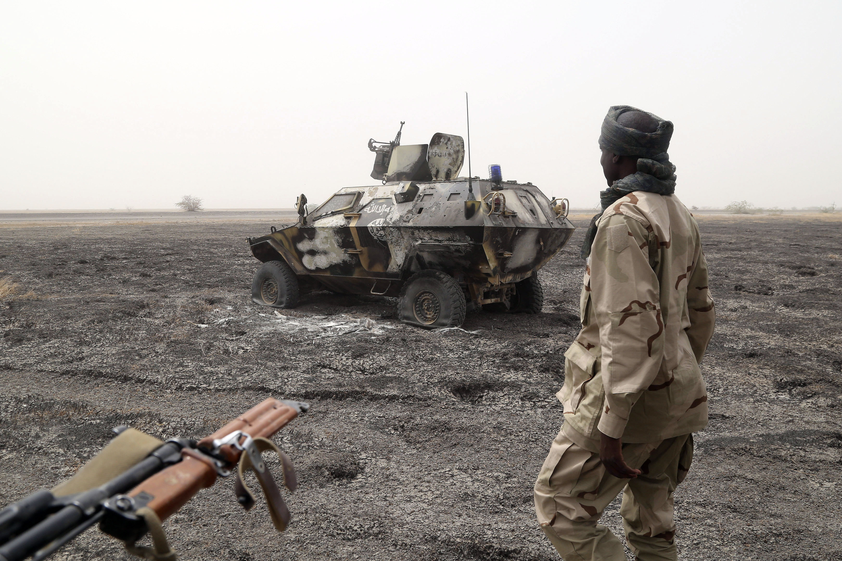 A Chadian soldier walks past an armored vehicle that the Chadian military said belonged to insurgent group Boko Haram.