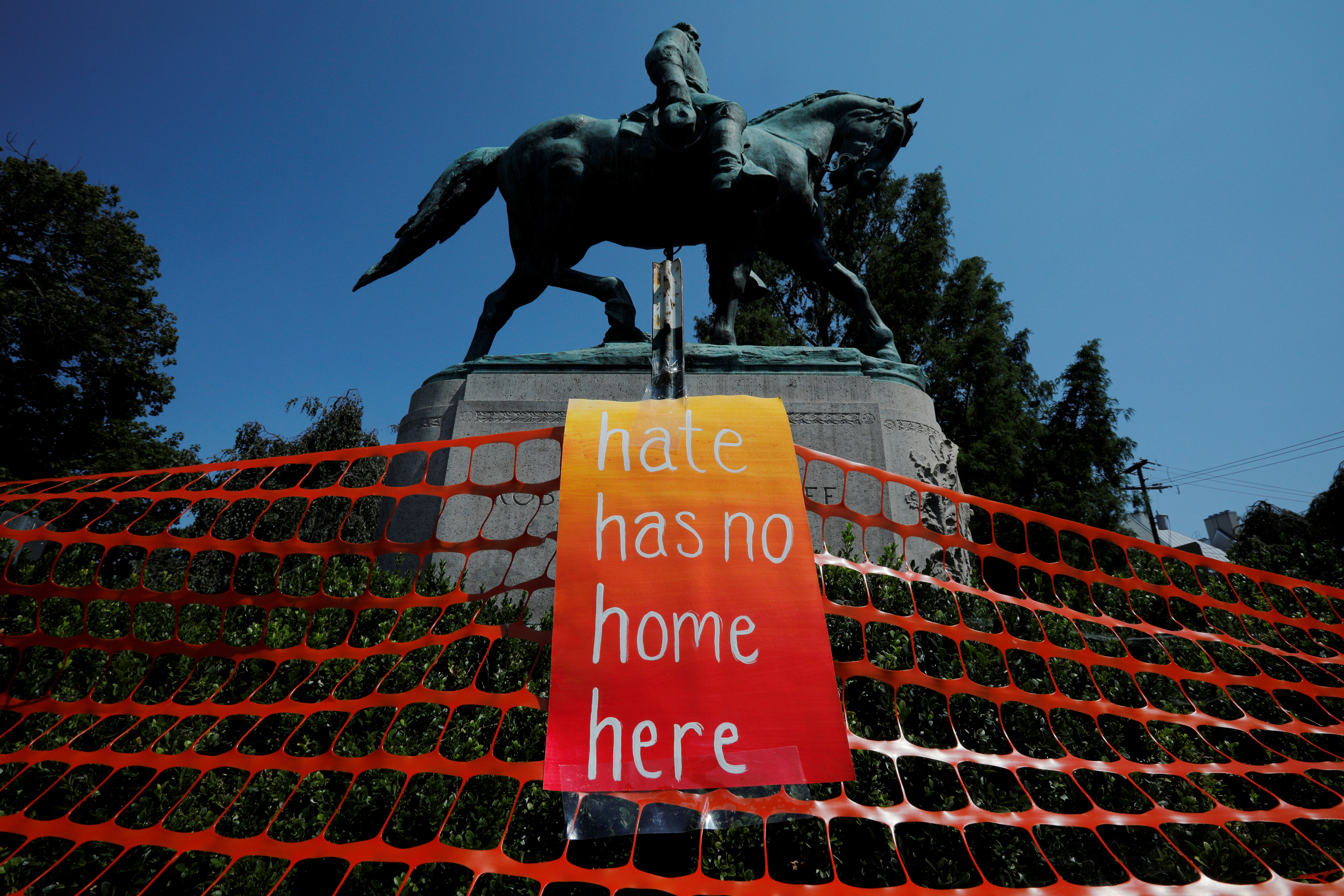 A sign reading 'Hate Has No Home Here' hangs by the statue of Civil War Confederate General Robert E Lee before the first anniversary of the 2017 Charlottesville, Virginia protests [File: Brian Snyder/Reuters]
