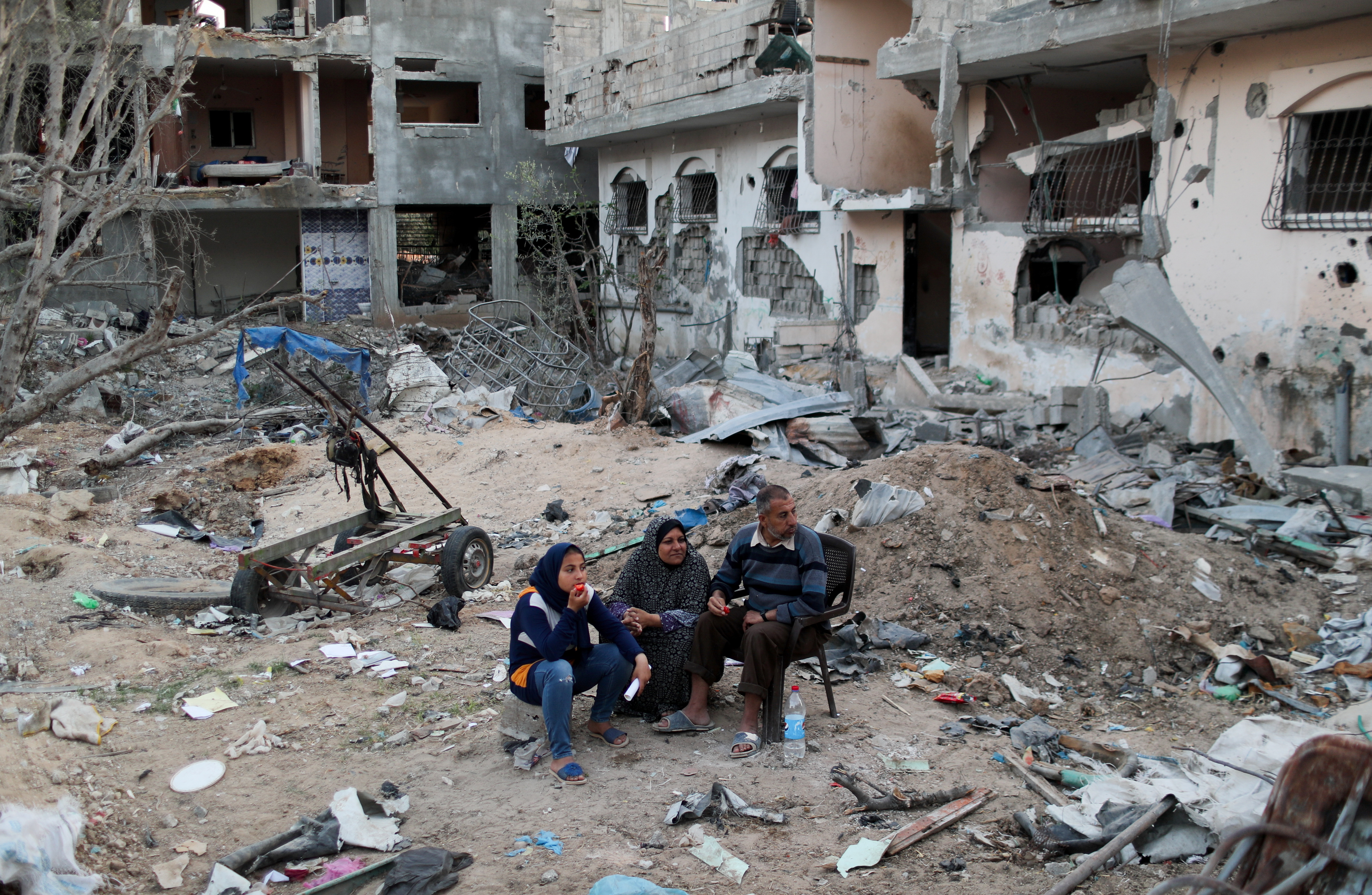 Palestinians sit near houses destroyed by Israeli bombardment, in the northern Gaza Strip June 1, 2021 [Mohammed Salem/Reuters]
