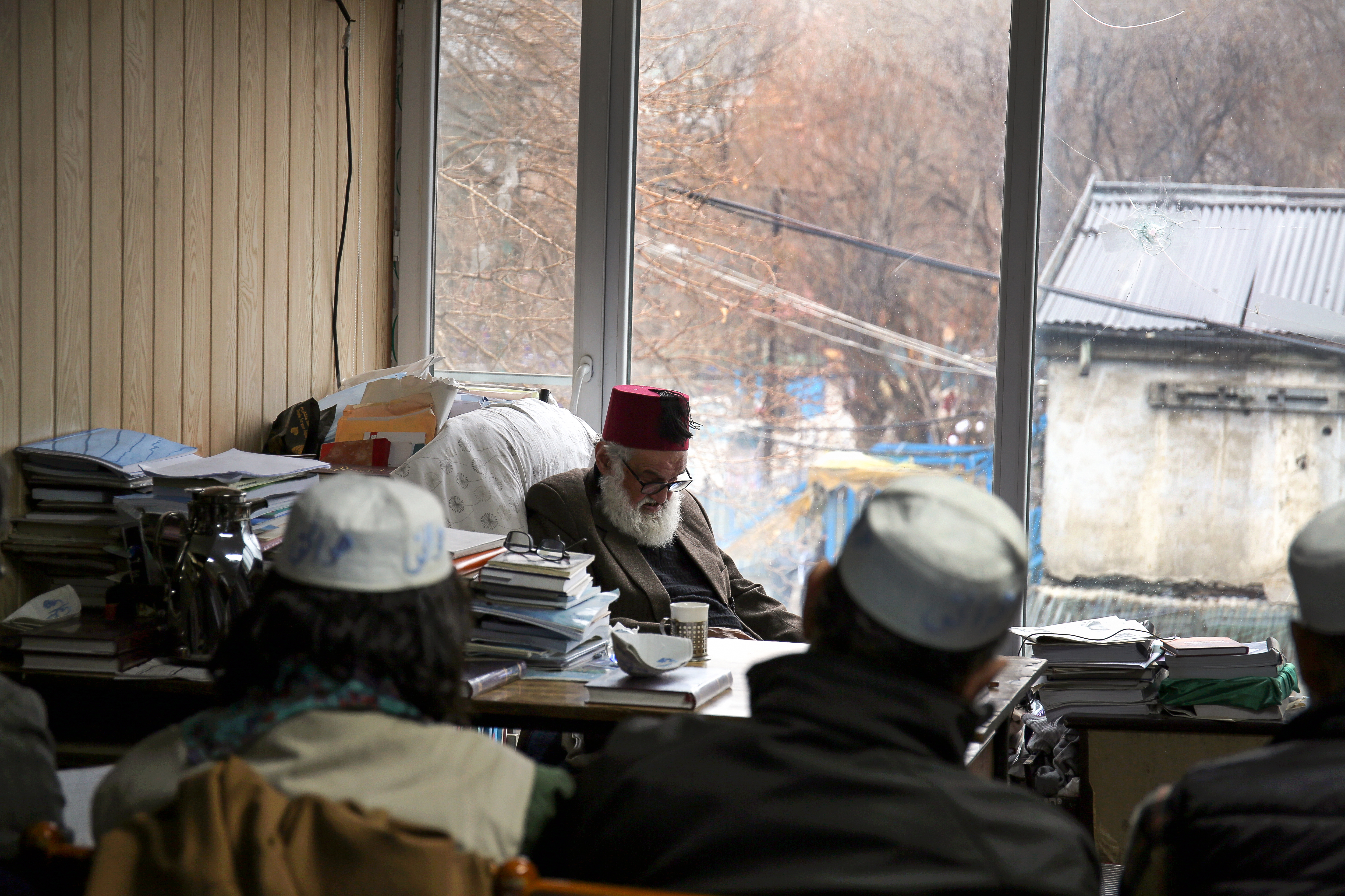 Eighty-one-year old Sufi mystic and poet Haidari Wujodi sits at his desk in Kabul Public Library [Lynzy Billing/Al Jazeera]