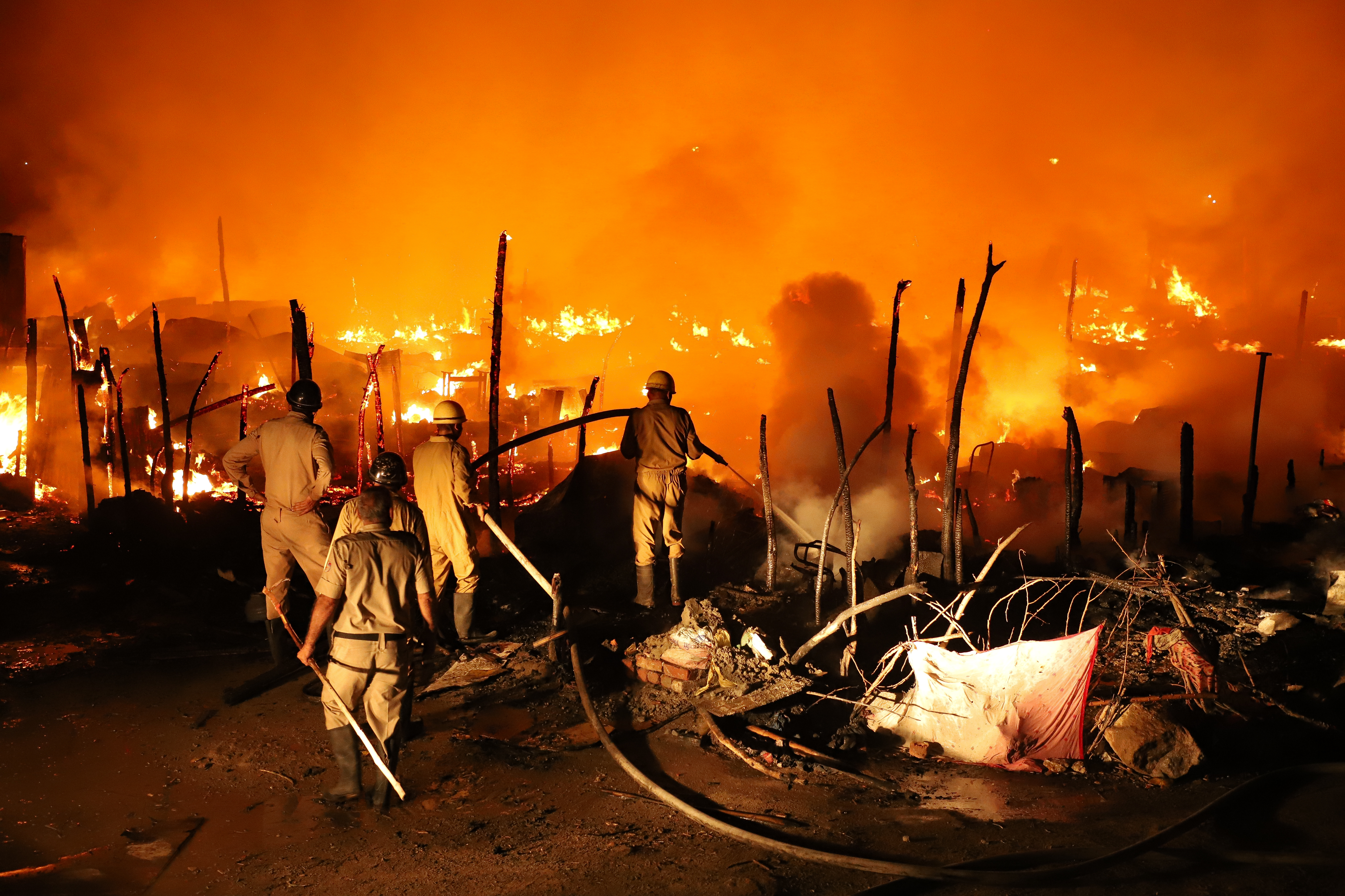 Firefighters douse the flames as fire rips through a Rohingya camp, reducing it to ashes in New Delhi [Meer Faisal/Al Jazeera]