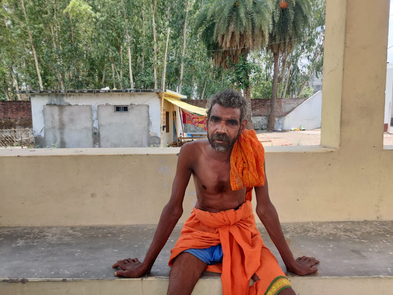 Deen Dayal Verma, a crematorium worker in Barabanki, Uttar Pradesh, sits in the shade inside the crematorium compound where he works [Saurabh Sharma/Al Jazeera]