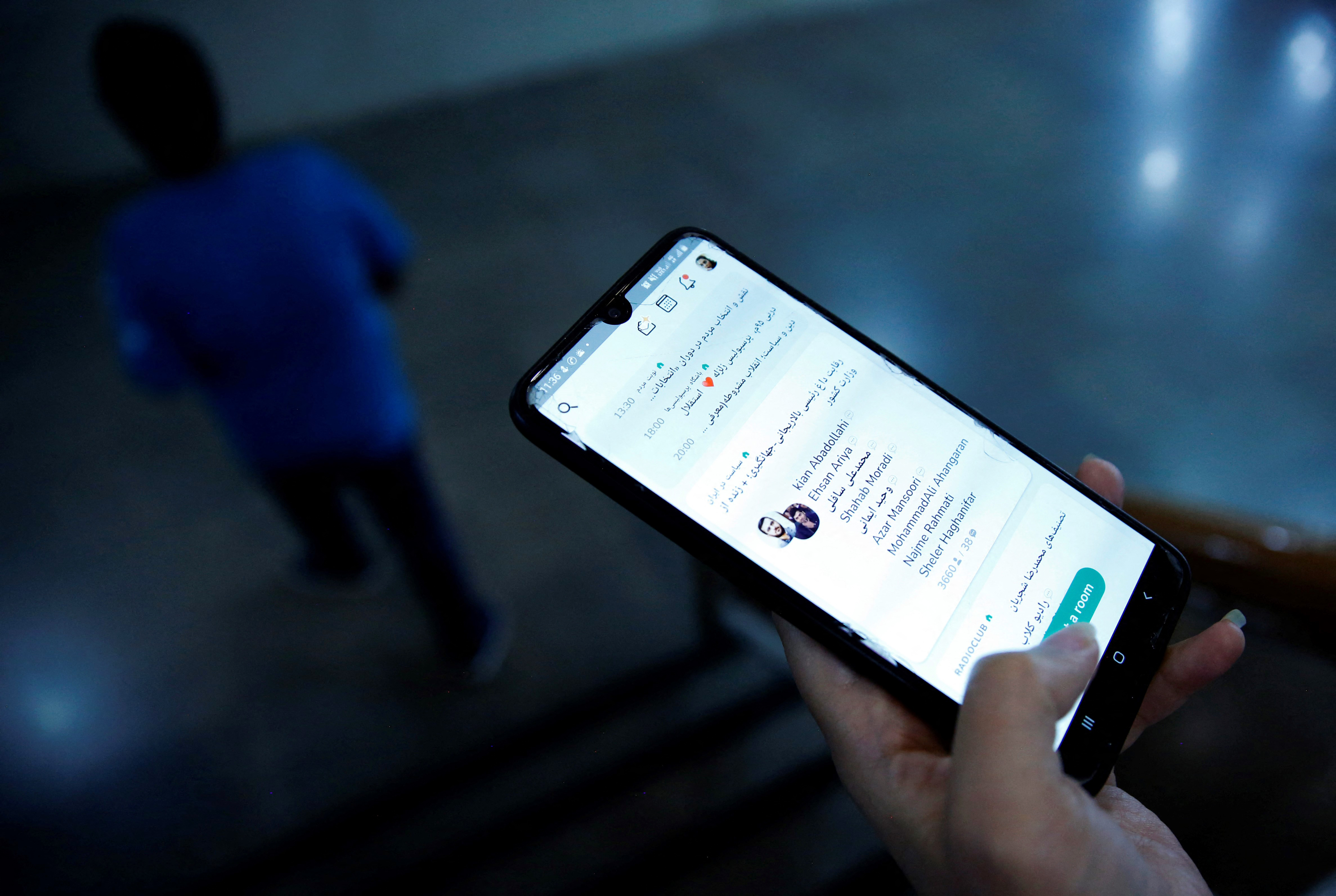 Iranian man checking the Clubhouse App on his smartphone