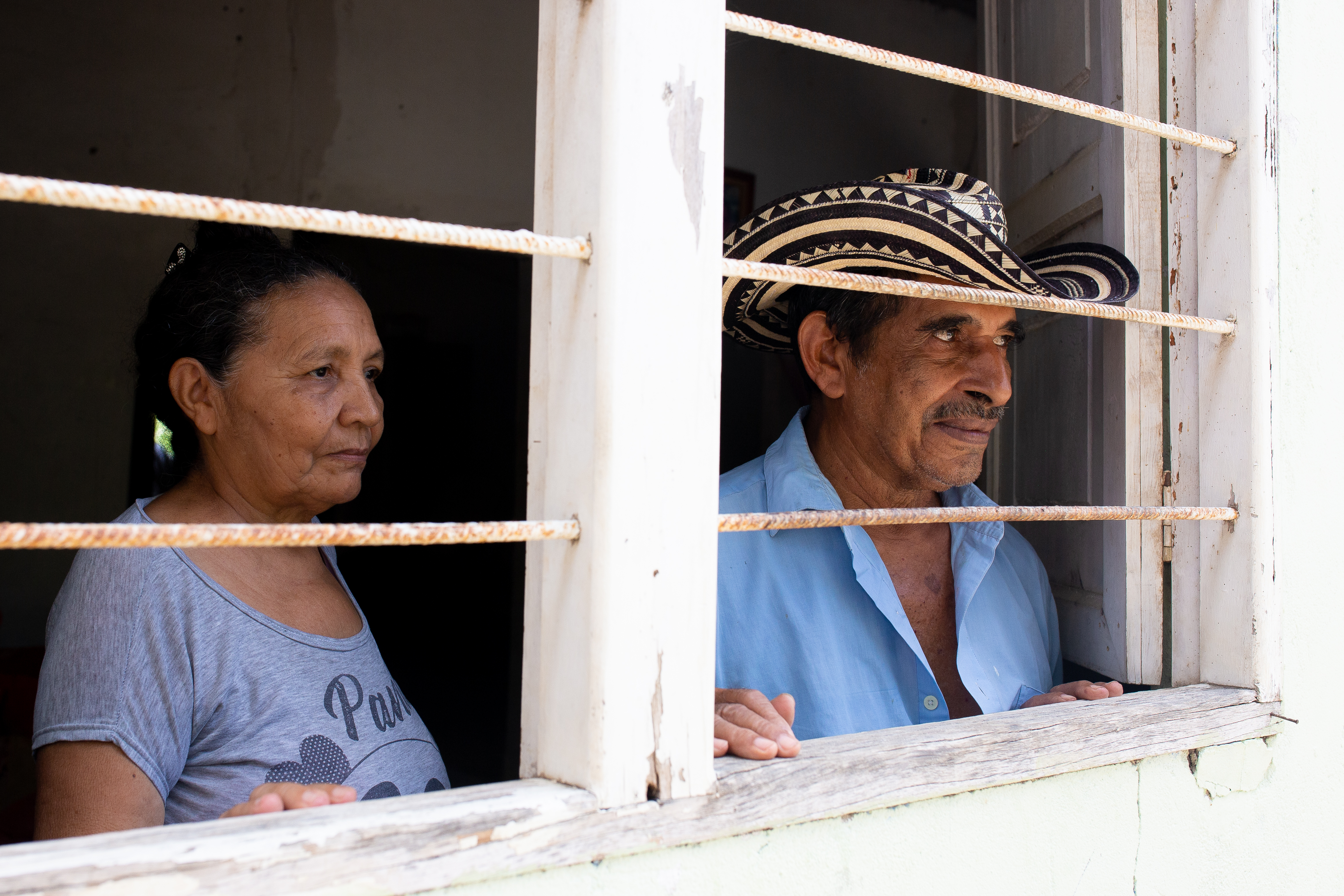 man and woman stare out a window with steel bars