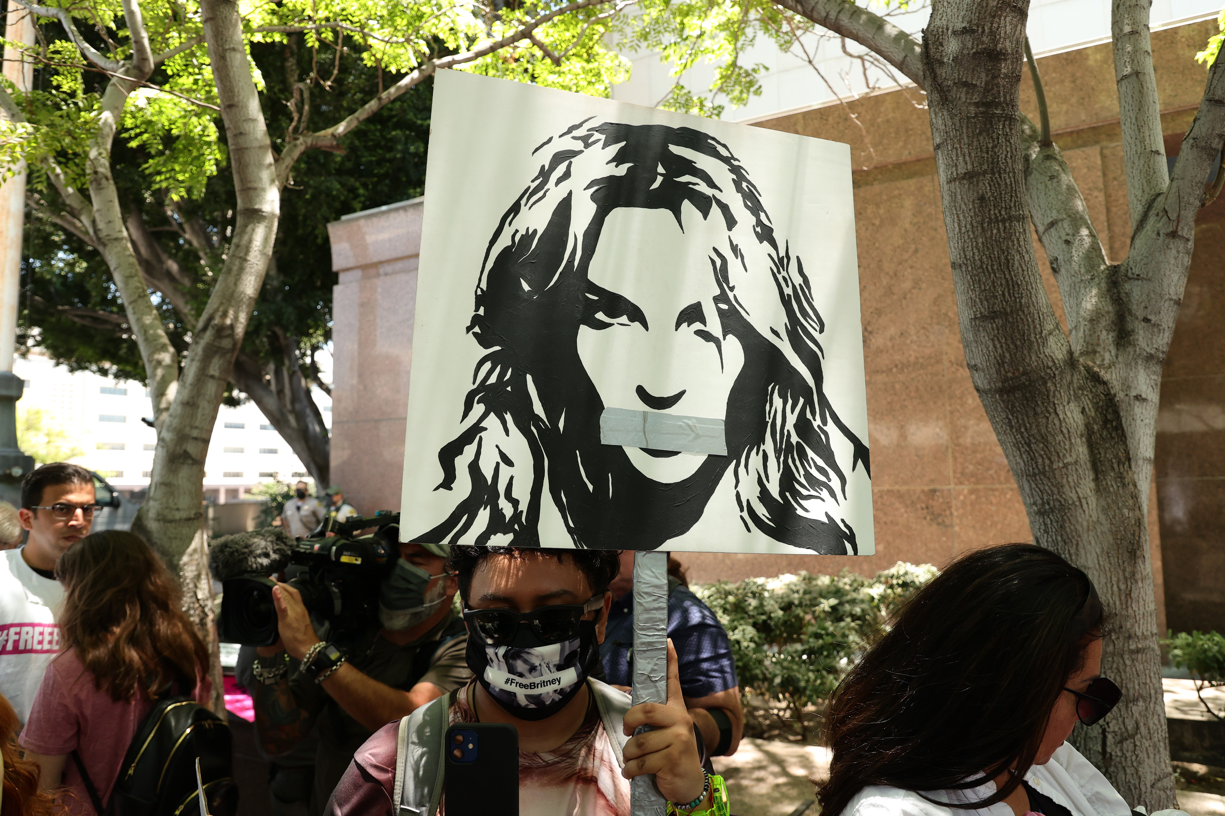#FreeBritney activists protest at Los Angeles Grand Park during a conservatorship hearing for Britney Spears on June 23, 2021 in Los Angeles, California. Spears is expected to address the court remotely. Spears was placed in a conservatorship managed by her father, Jamie Spears, and a lawyer, which controls her assets and business dealings, following her involuntary hospitalization for mental care in 2008 [Rich Fury/Getty Images]