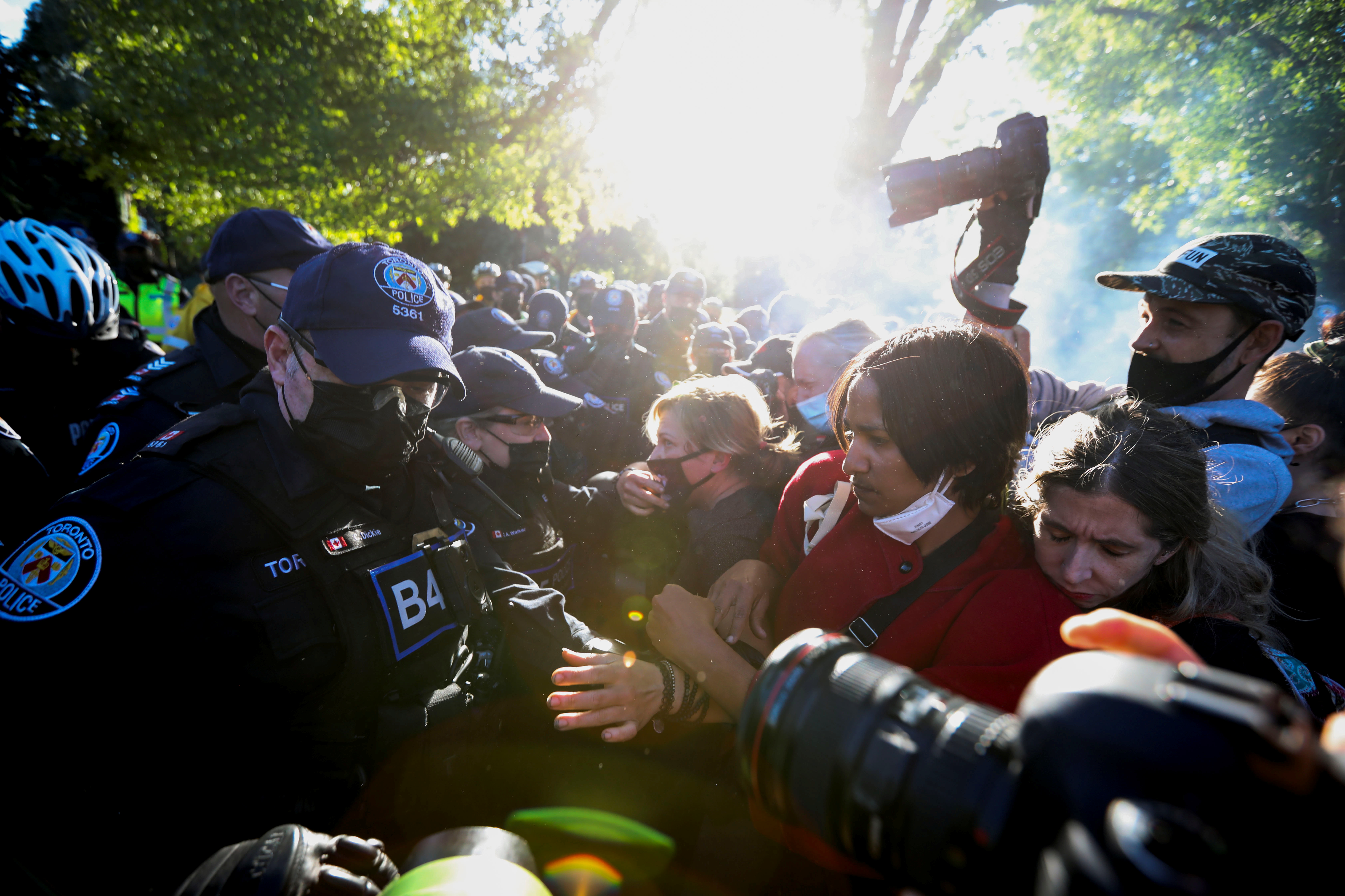 People scuffle with police officers after the eviction of two dozen people from a homeless encampment at Trinity Bellwoods Park in Toronto, Ontario, on June 22, 2021 [Carlos Osorio/Reuters]