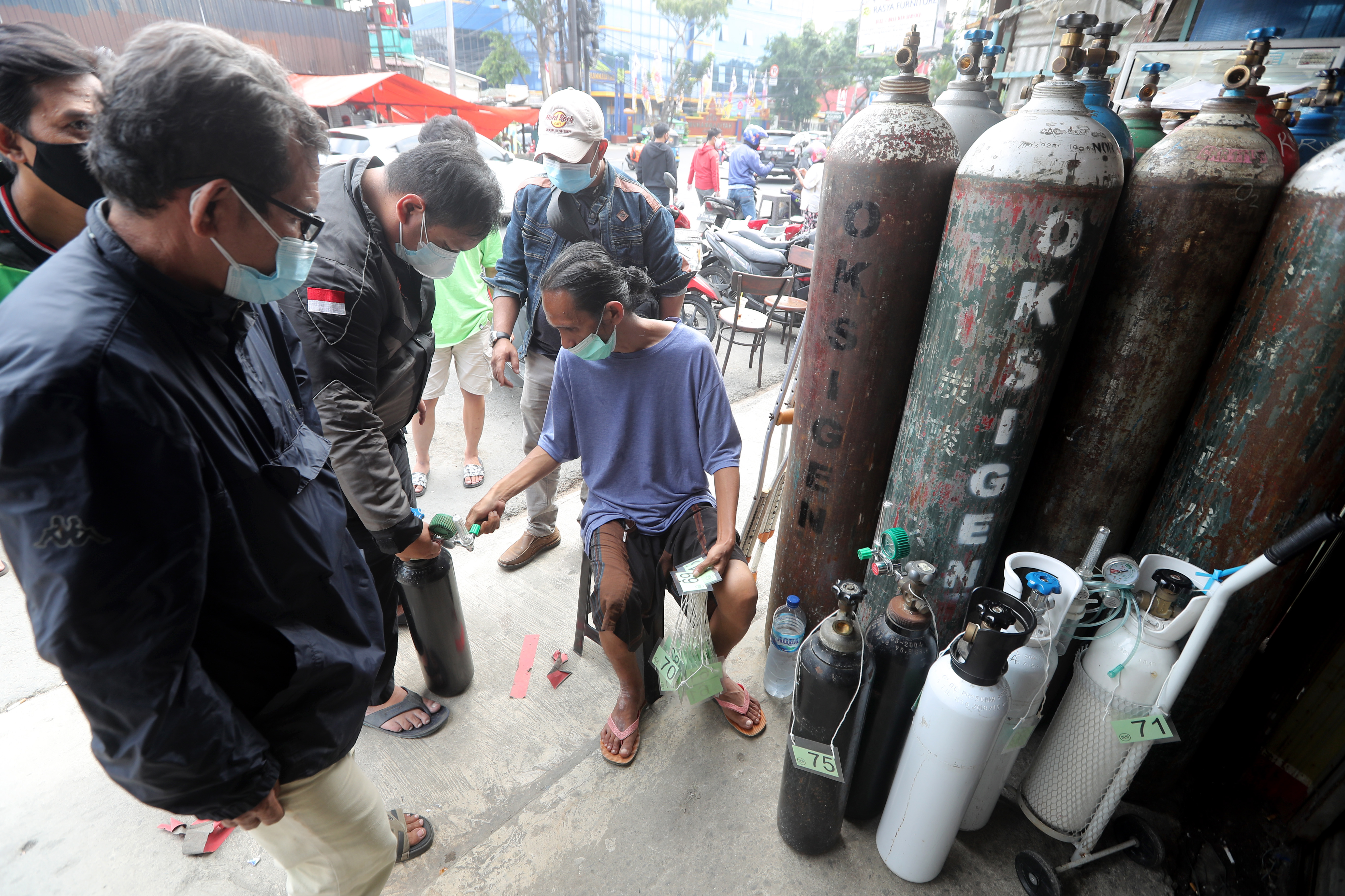 A worker checks the queue number at an oxygen refill shop in Jakarta. The surge in COVID-19 cases has led to soaring demand for oxygen [Bagus Indahono/EPA]