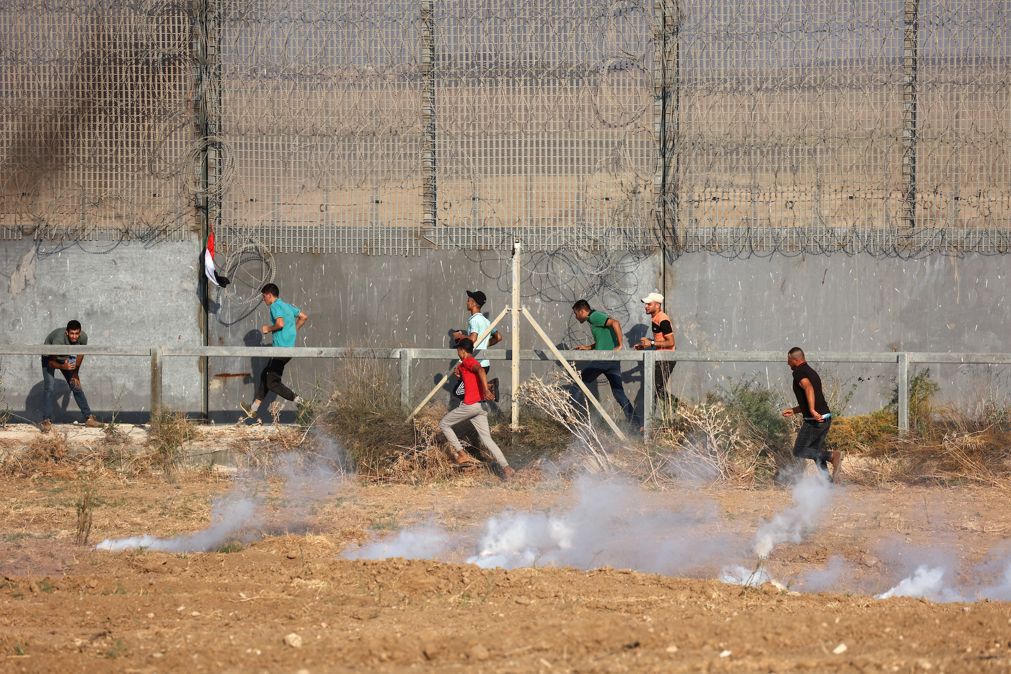 Palestinian protesters run as tear gas canisters are shot by Israeli forces, during a demonstration by the Israeli fence east of Gaza City, to denounce the Israeli siege of the Palestinian territory [Said Khatib/AFP]