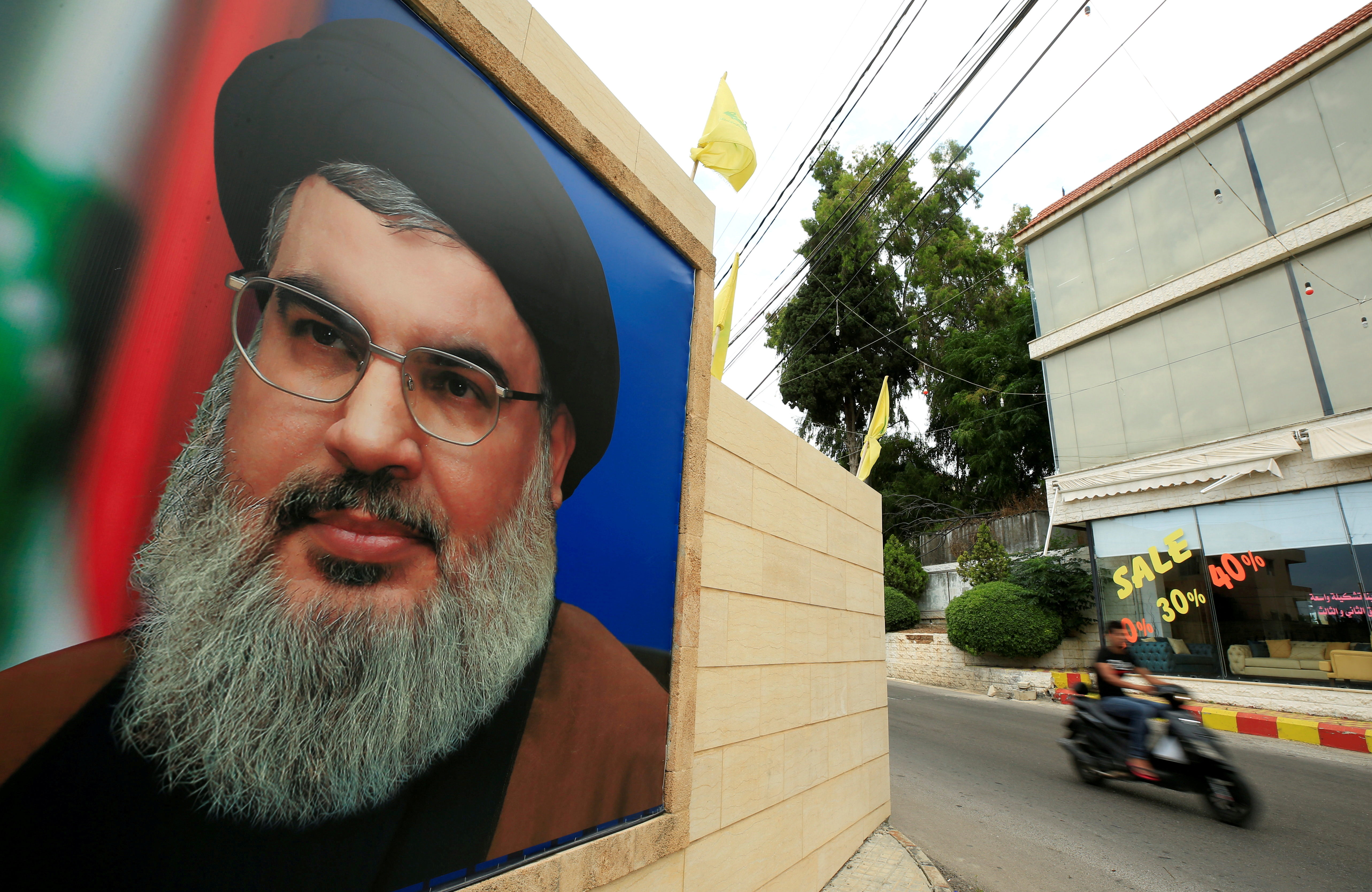 A man rides a motorbike past a picture of Lebanon's Hezbollah leader Sayyed Hassan Nasrallah, near Sidon, Lebanon