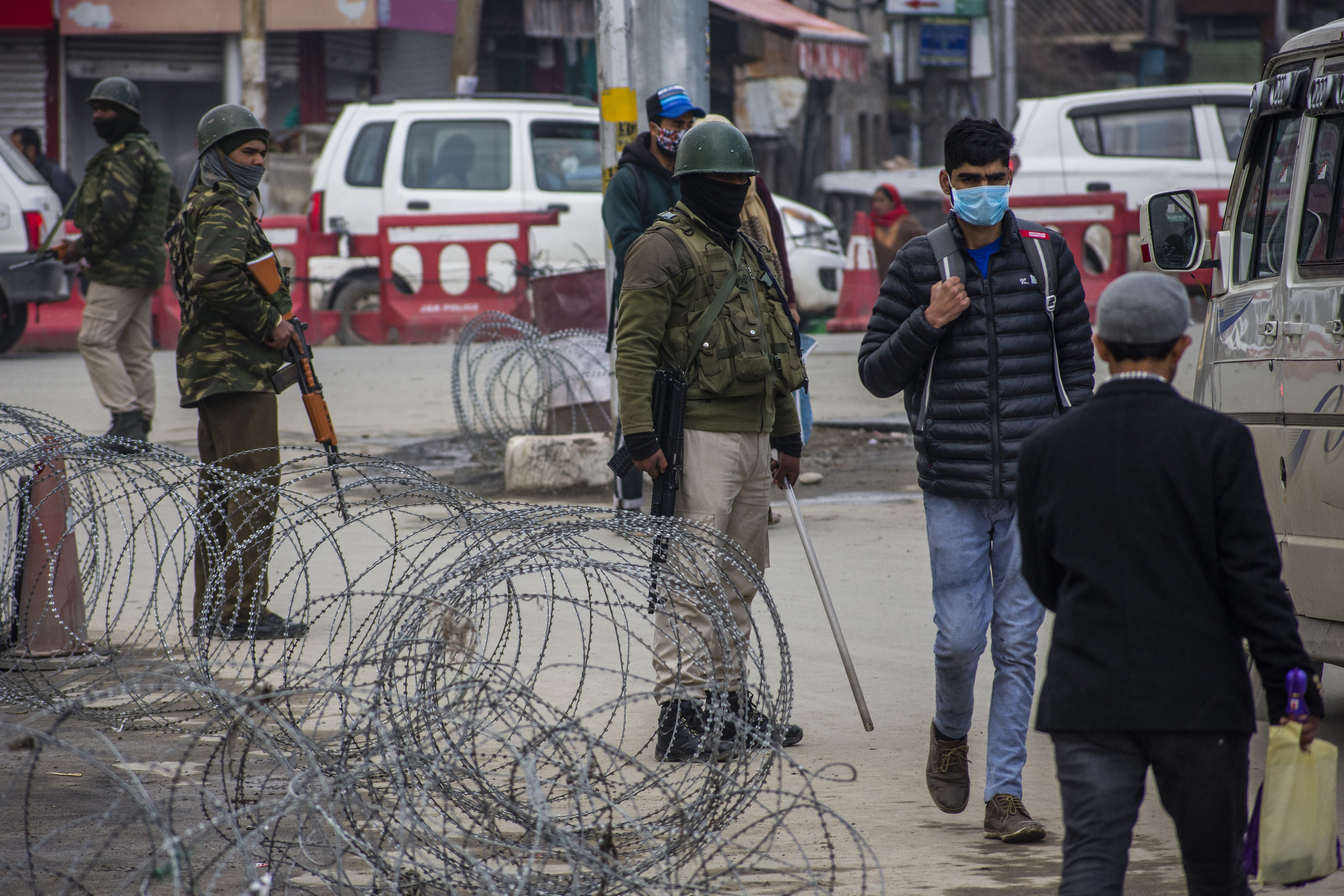 Kashmiris walk in front of Indian government forces guarding their bunkers on a main road, on March 15, 2021, in Srinagar, the summer capital of Indian administered Kashmir [Yawar Nazir/Getty Images]