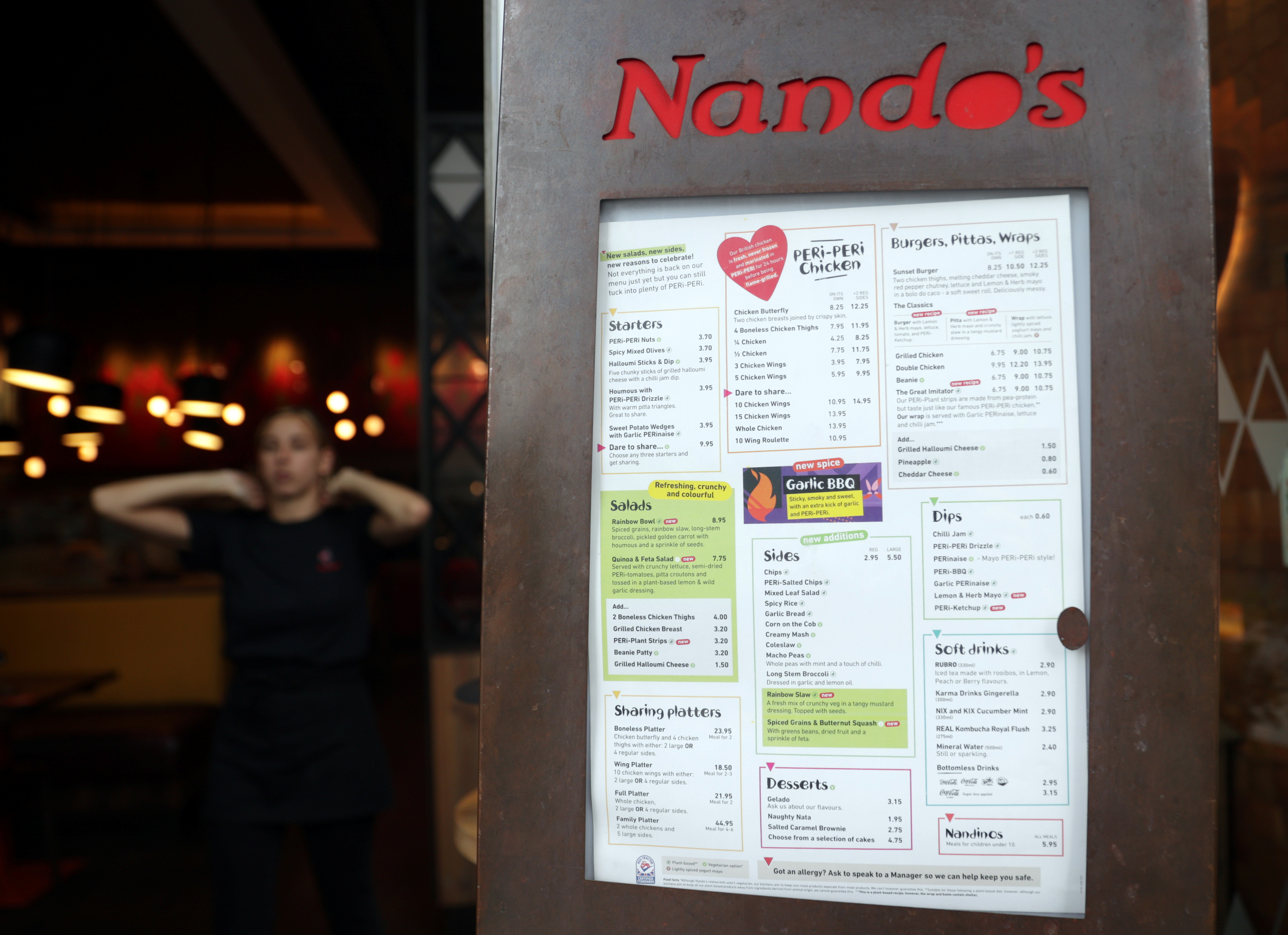 A menu is seen on display outside a Nando’s restaurant in London, UK, August 18, 2021 [File: Hannah McKay/Reuters]