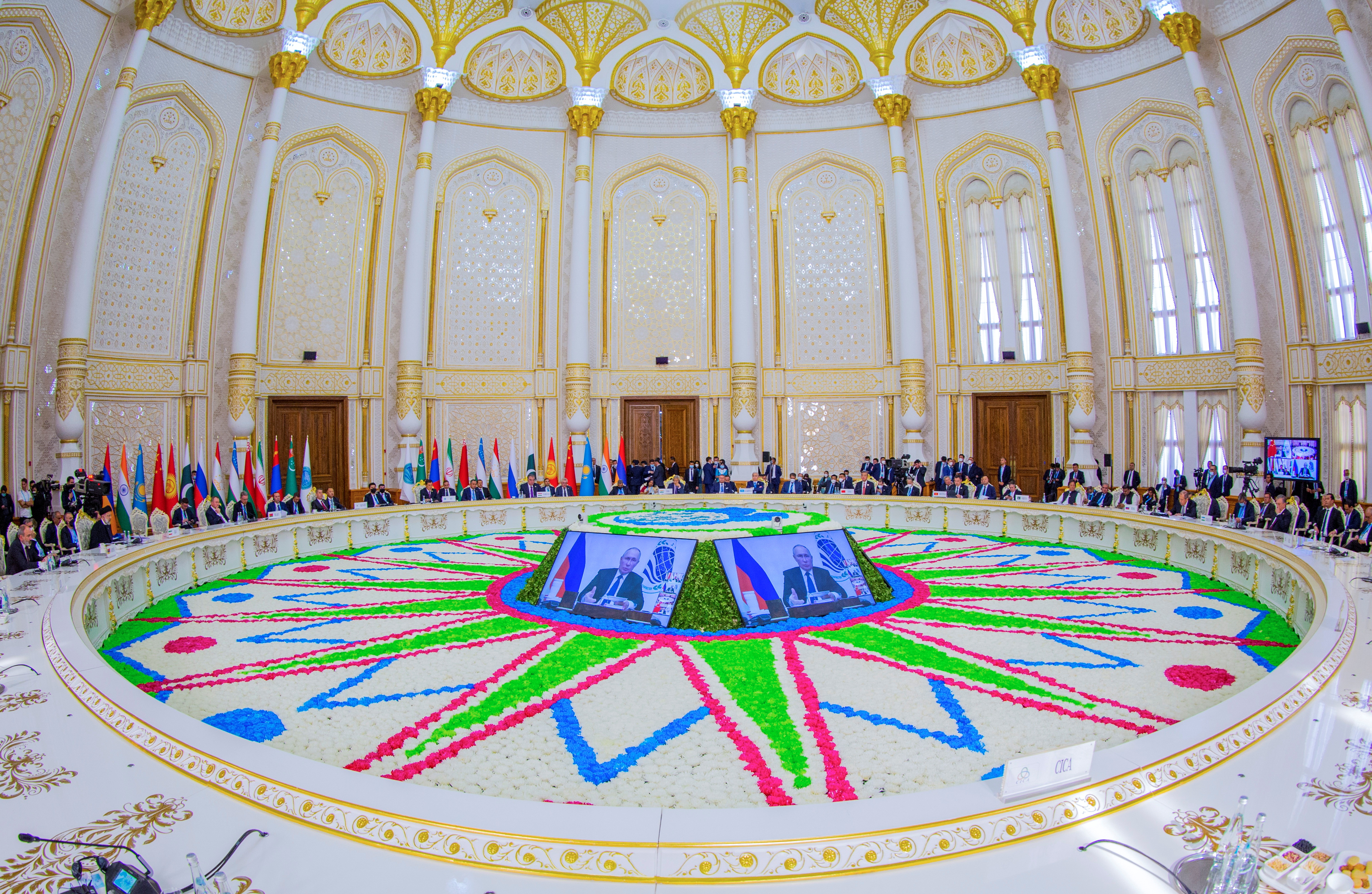 Summit participants listen as Russian President Vladimir Putin delivers a speech via a video link