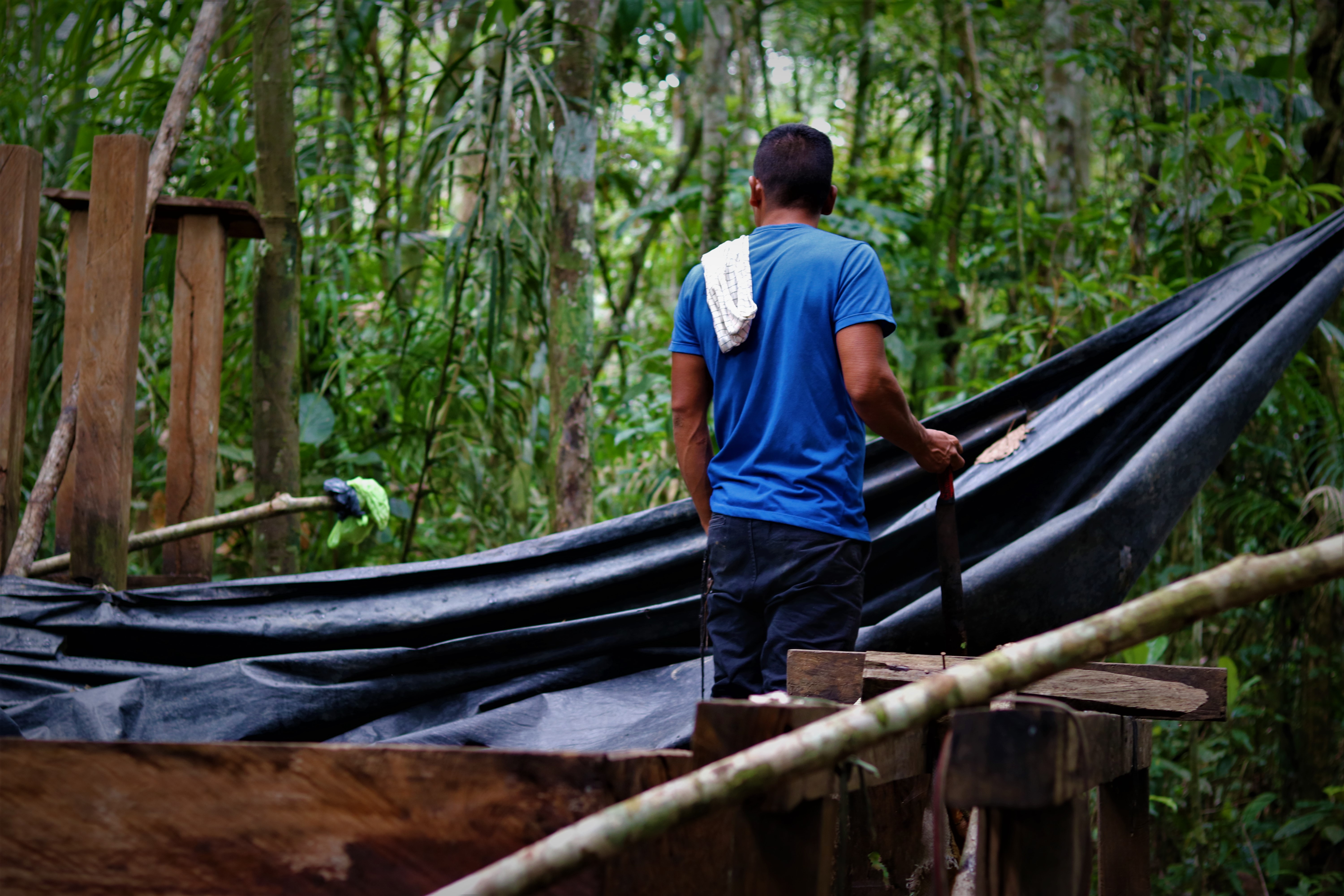 Henri, a Colombian coca farmer, stands by a piece of fallen tarp at a makeshift laboratory near his coca patch in the country's Guaviare department [Steven Grattan/Al Jazeera]