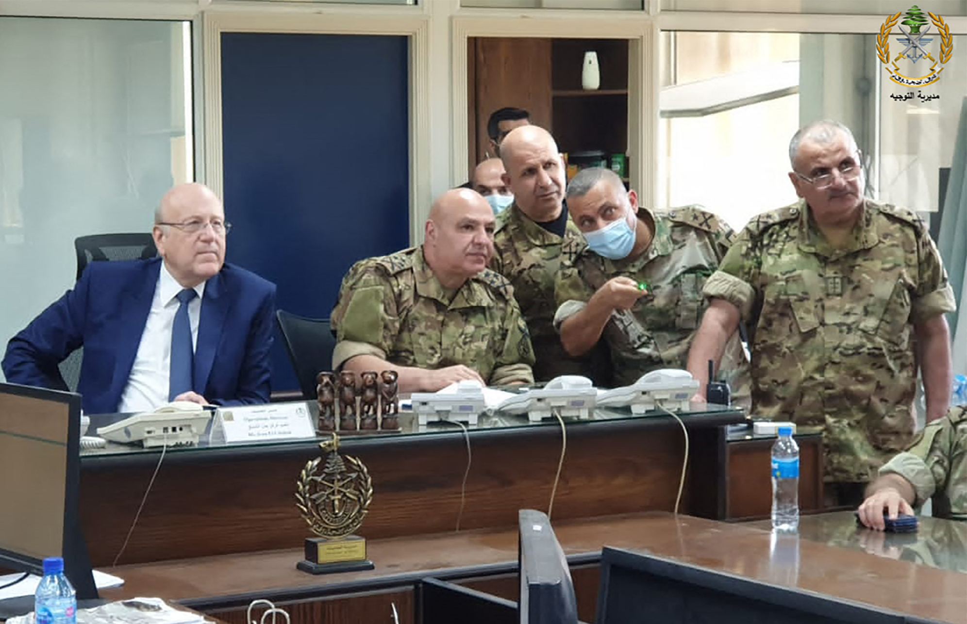 A handout picture provided by the Lebanese army website shows Lebanon's Prime Minister Najib Miqati (L) meeting with Lebanese Army Chief Joseph Aoun (C) and other military officials at the ministry of defence in Yarze, on the eastern outskirts of the capital Beirut on October 14, 2021. - Tank deployments and deadly exchanges of fire turned Beirut into a war zone after a demonstration organised by Shiite Muslim parties against the lead investigator into last year's devastating port blast turned violent. (Photo by STRINGER / Lebanese Army Website / AFP) / === RESTRICTED TO EDITORIAL USE - MANDATORY CREDIT "AFP PHOTO / HO / Lebanese Army website" - NO MARKETING - NO ADVERTISING CAMPAIGNS - DISTRIBUTED AS A SERVICE TO CLIENTS ===