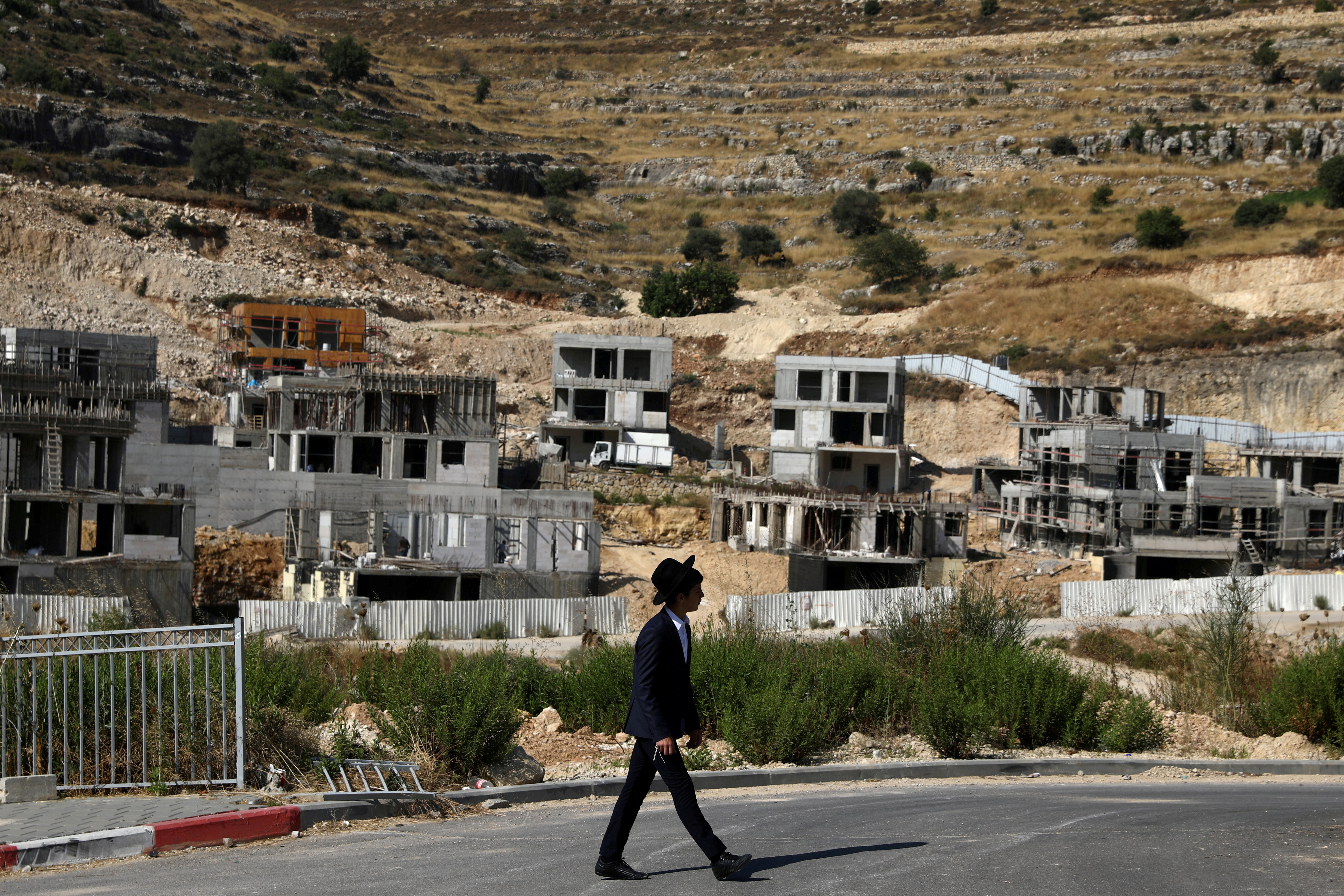 A Jewish settler walks past Israeli settlement construction sites around Givat Zeev and Ramat Givat Zeev in West Bank