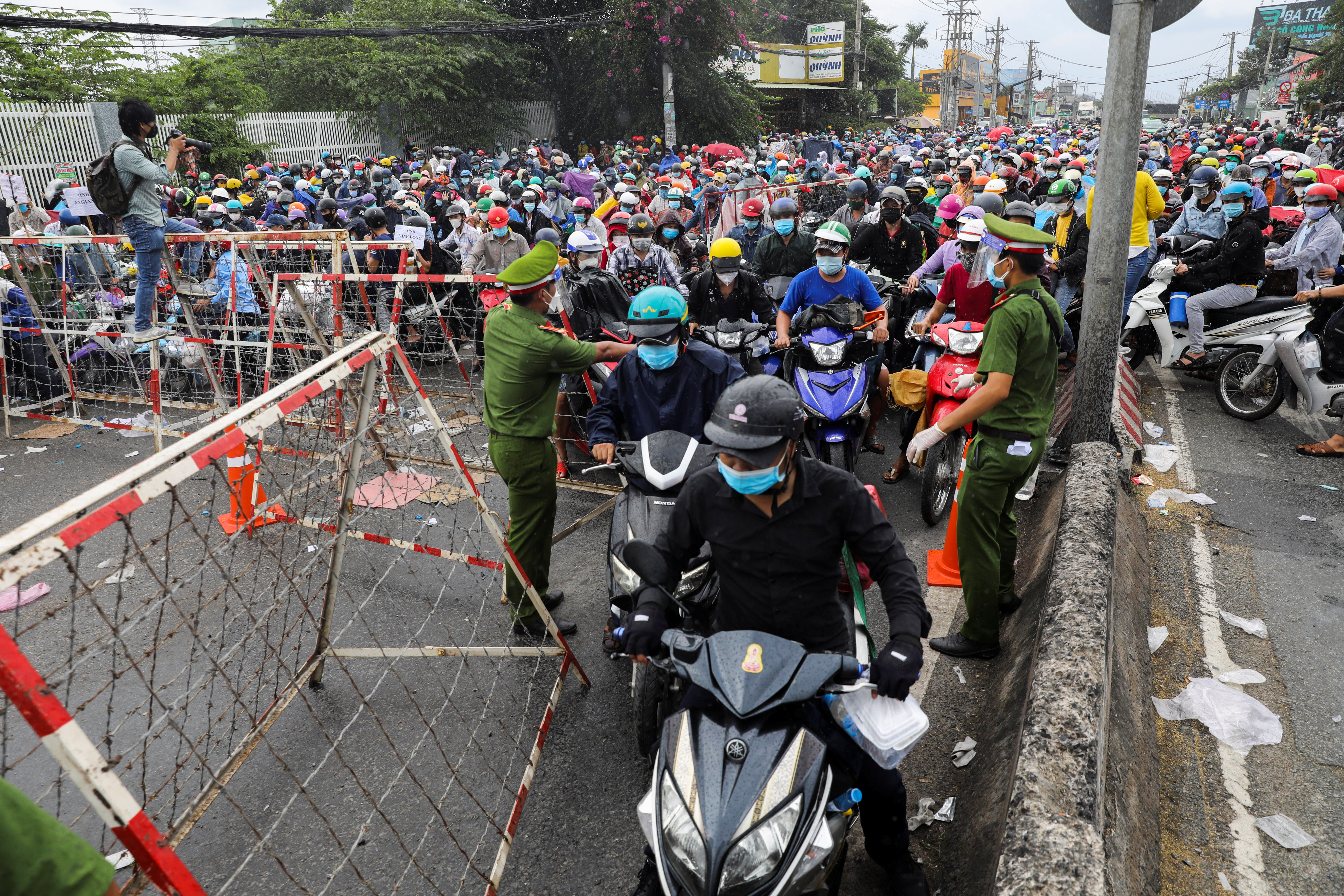 People, mostly migrant workers who are planning to return to their hometowns, wait at a checkpoint to leave Ho Chi Minh City on October 1, 2021 [Stringer/ Reuters]