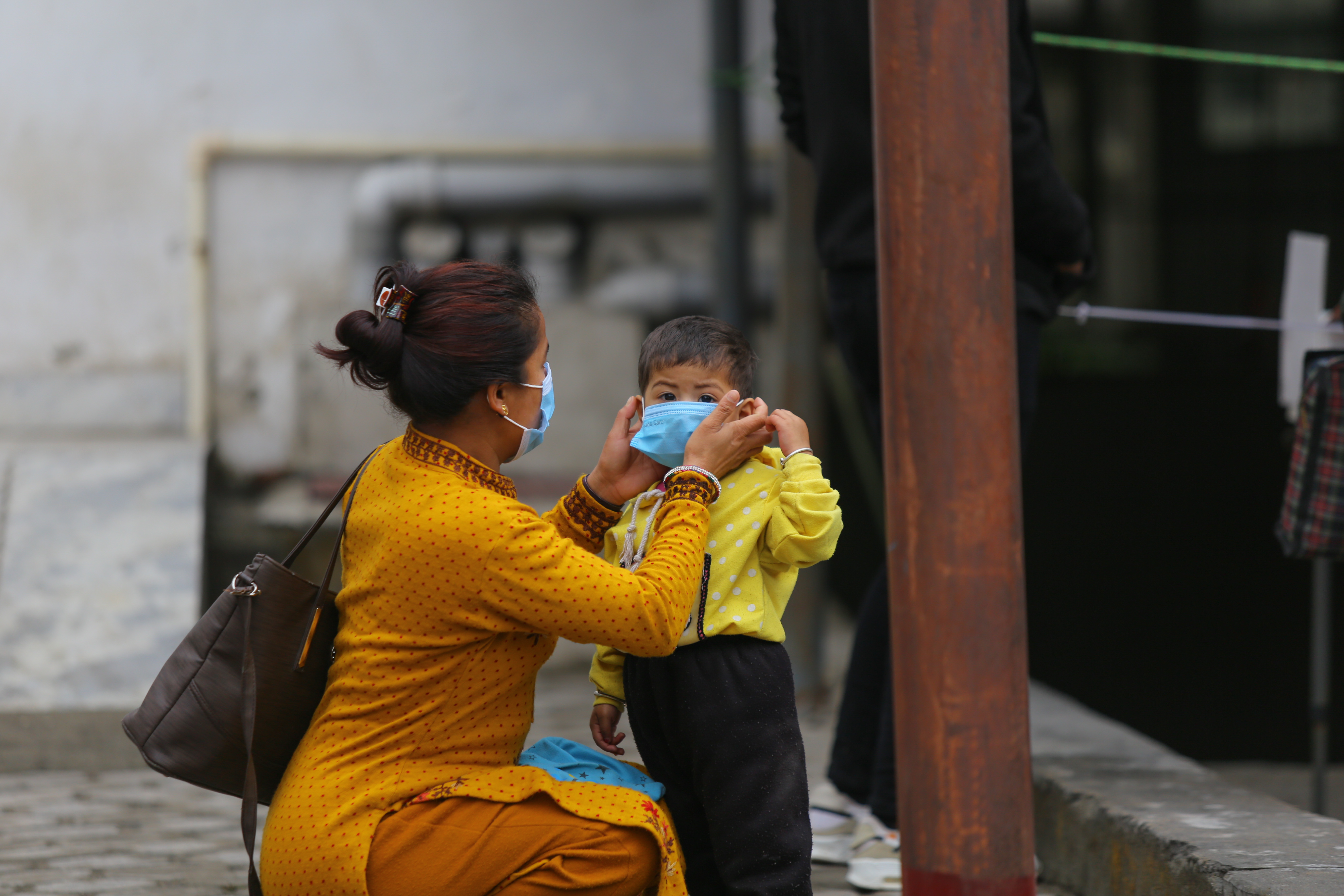 A woman arranges the facial mask of a child amid the ongoing coronavirus COVID-19 pandemic in Kathmandu, Nepal on May 2, 2021. [Sunil Pradhan/NurPhoto via Getty Images]