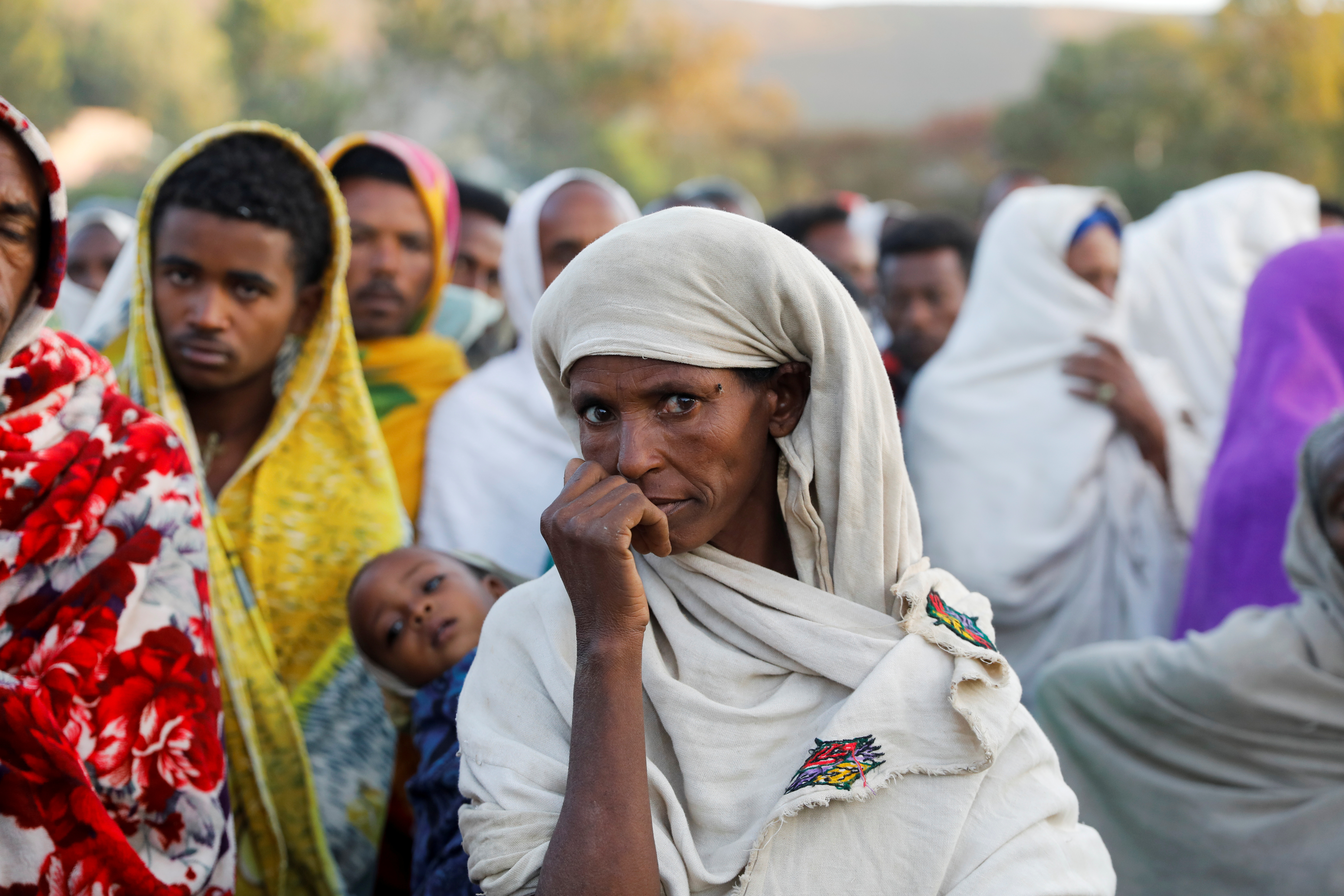 A woman stands in line to receive food donations, at the Tsehaye primary school, which was turned into a temporary shelter for people displaced by conflict, in the town of Shire, Tigray region, Ethiopia