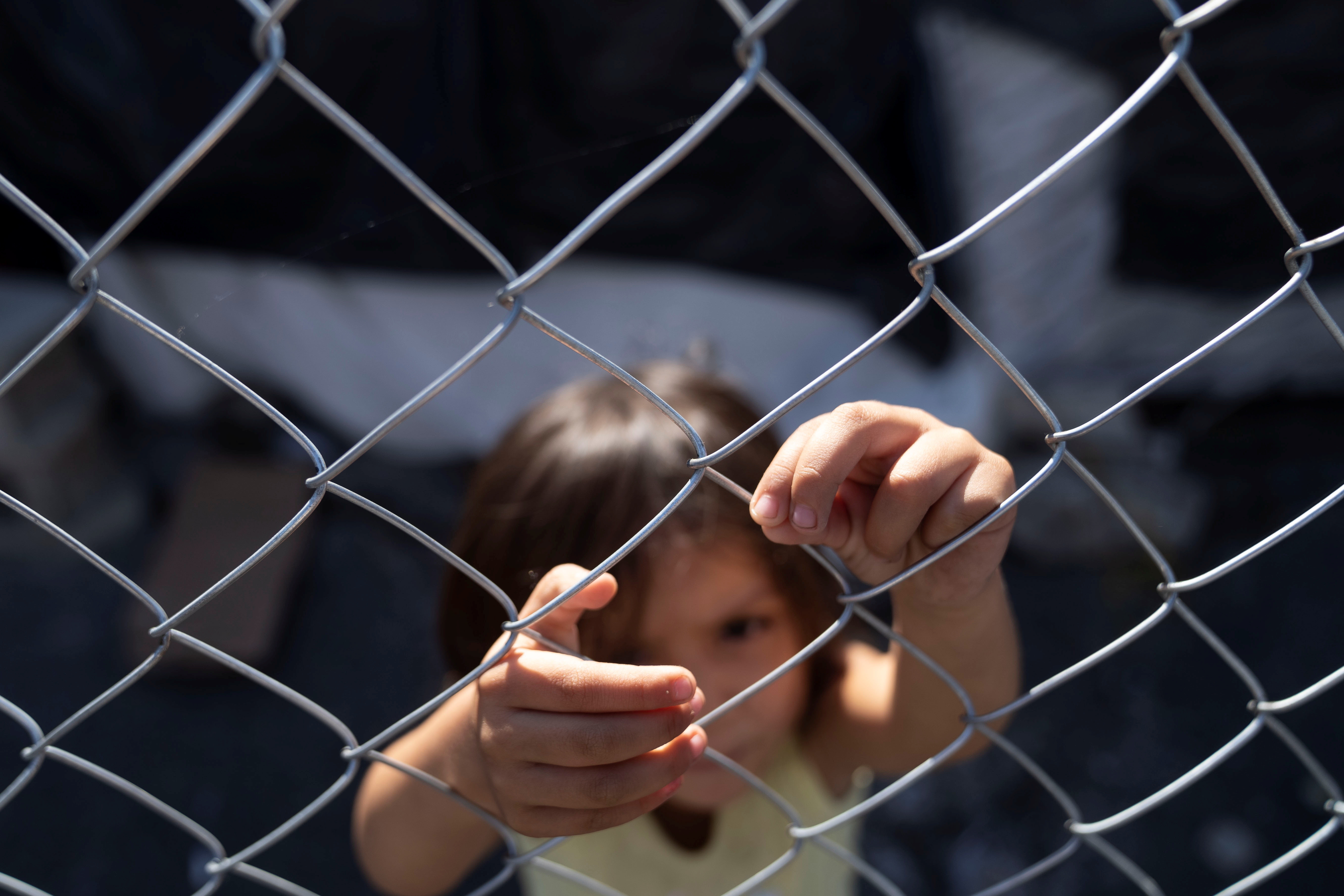 A girl plays at a fence in Tijuana