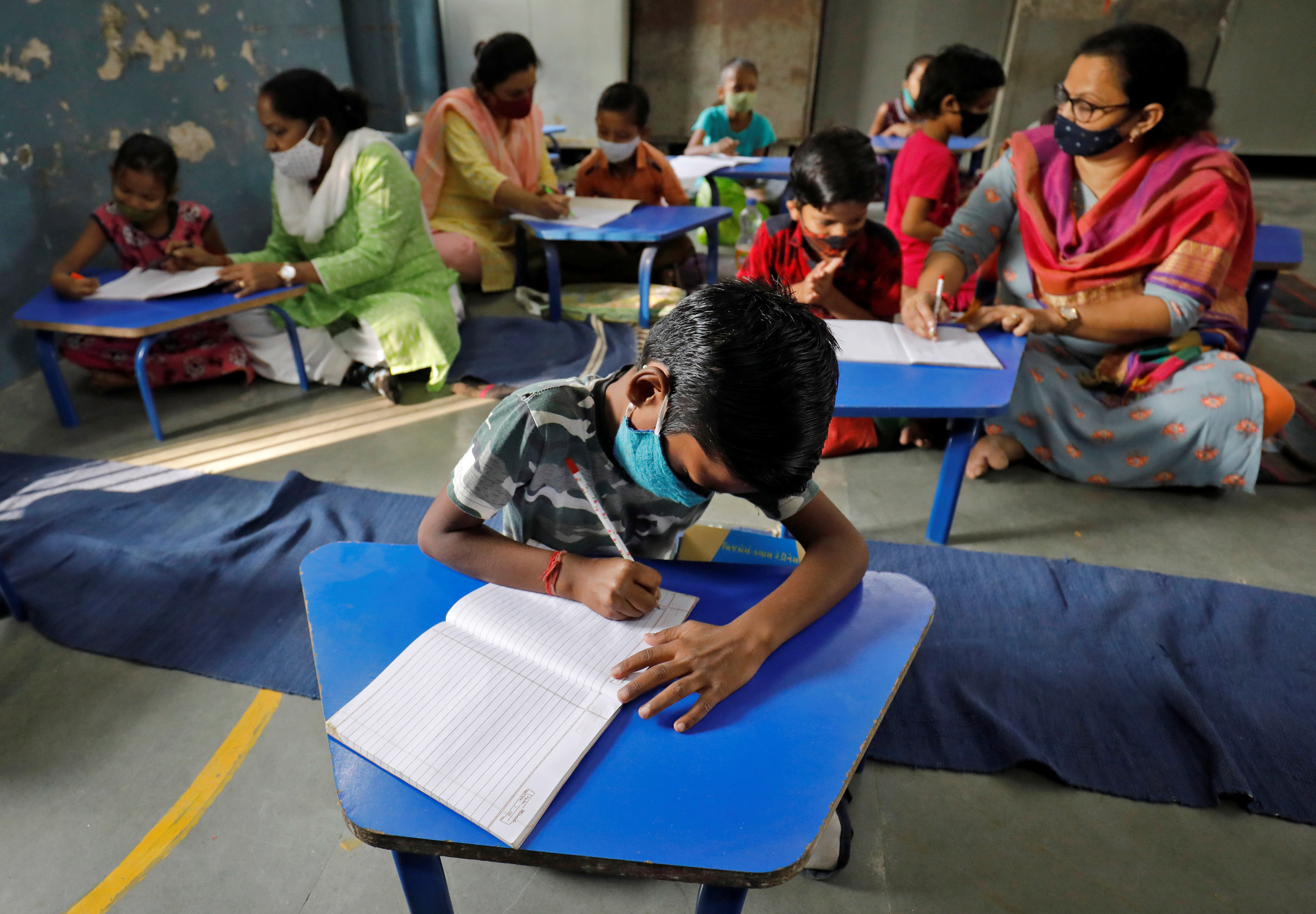 School students and their teachers, wearing protective face masks, attend a class following the reopening of the primary schools after months of closure due to the coronavirus disease outbreak in Ahmedabad, India [Amit Dave/Reuters]