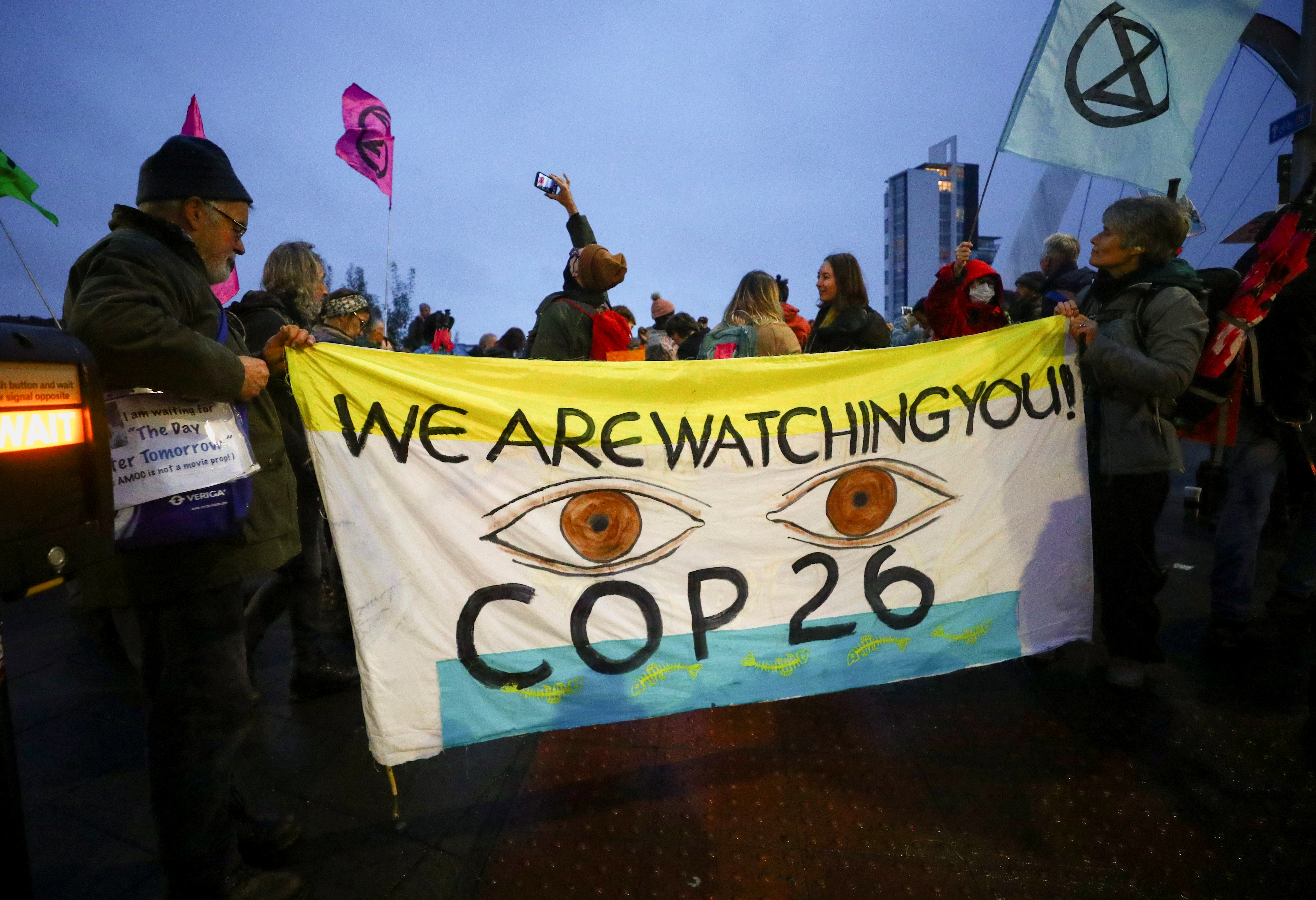 Extinction Rebellion activists hold a banner during a protest outside COP26 in Glasgow [Hannah McKay/Reuters]